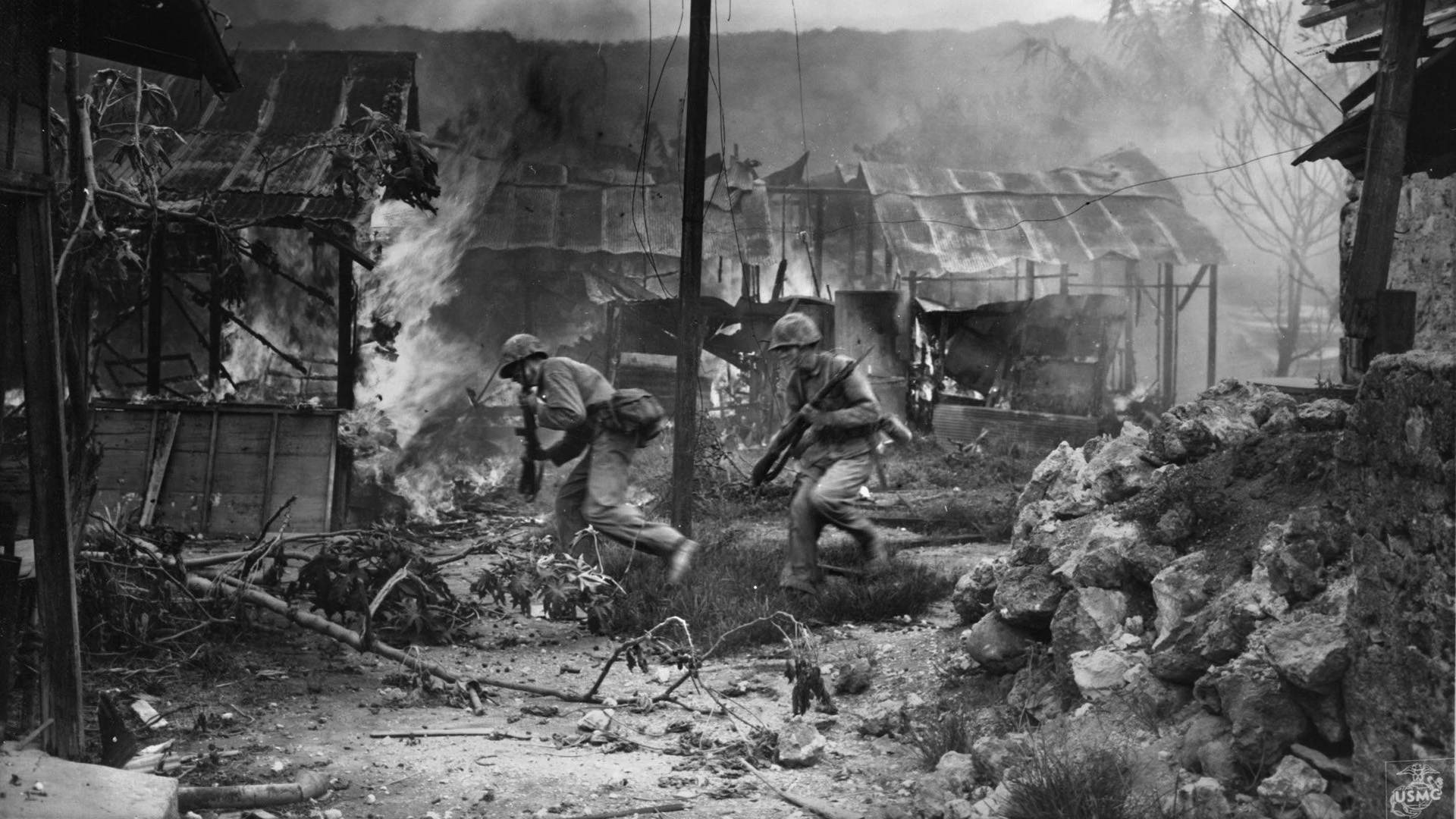 Under heavy fire from Japanese defenders, Marines move quickly through the rubble of Garapan, principal city on the island of Saipan. The battle for Garapan in July 1944 was the first experience of street fighting for American Marines in the Pacific.