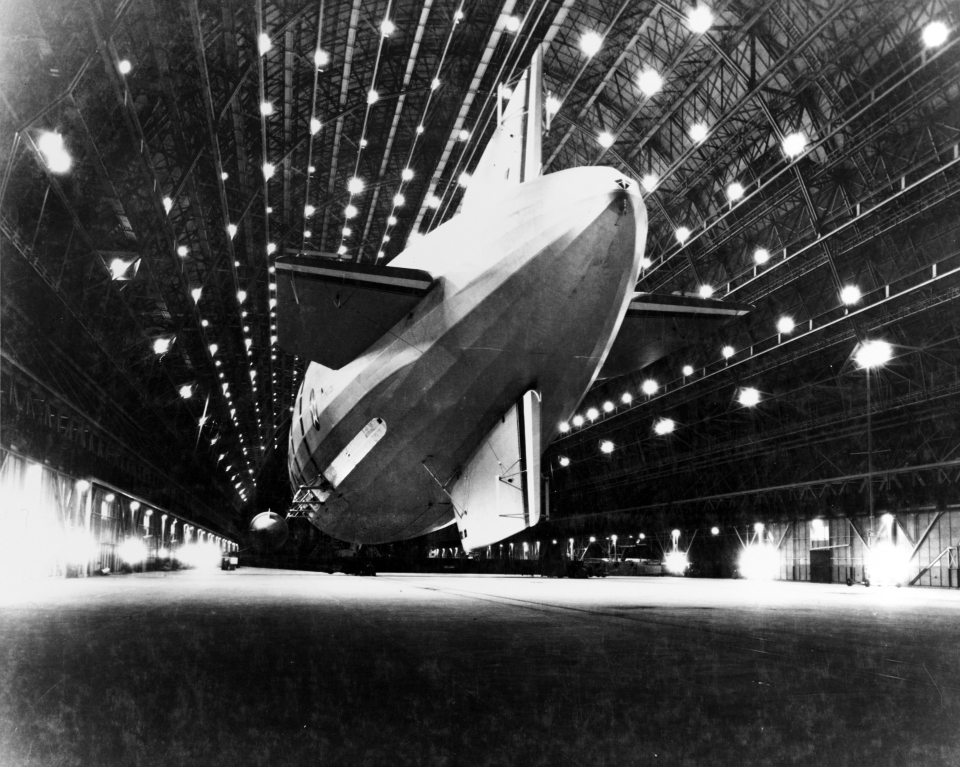 The immense airship USS Macon is shown docked in its hangar at Naval Air Station Moffet Field, Sunnyvale, California, in October 1933.  This photo was taken following a cross-country flight from Lakehurst, New Jersey, and months before the airship was damaged during a storm and lost off the coast of Big Sur, California, in 1935. Most fo the crew was rescued, and the wreckage is listed as the USS Macon Airship Remains on the U.S. National Register of Historic Places.