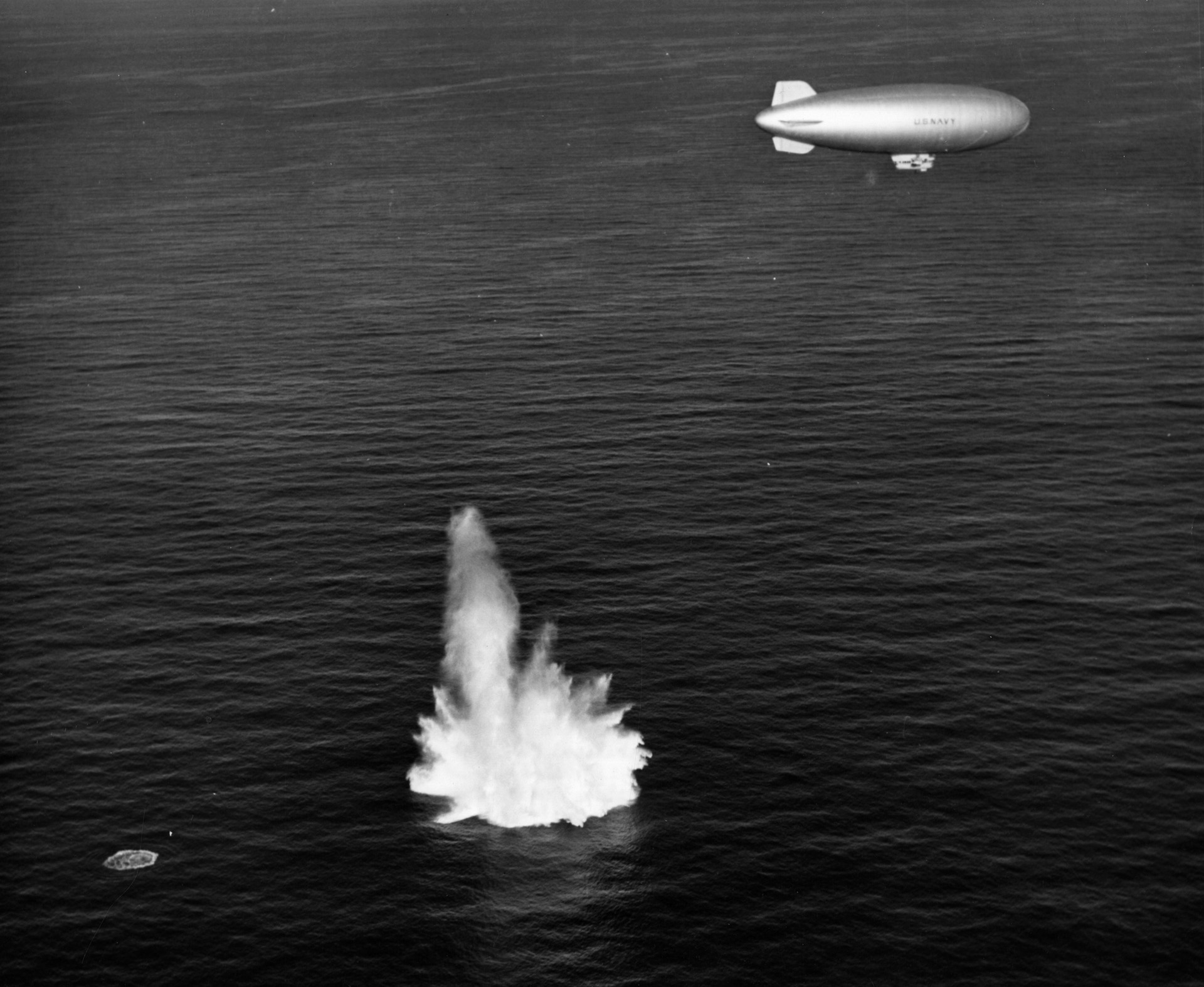A U.S. Navy blimp drops a depth charge into the ocean during exercises in 1943. This target practice sequence occurred off the coast of New Jersey and the base at Lakehurst, which had gained fame as the site of the destruction of the German airship Hindenburg in 1937.