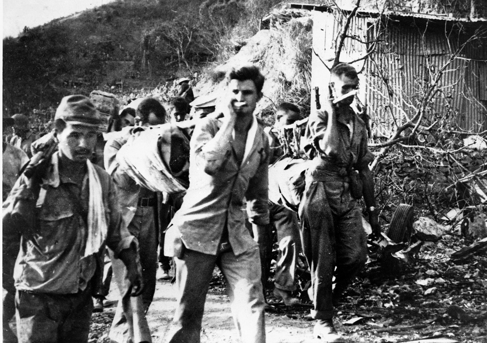 American prisoners carry a wounded comrade on a stretcher during the Bataan Death March. The Japanese committed many atrocities against the prisoners, who died in great numbers on the arduous trek.