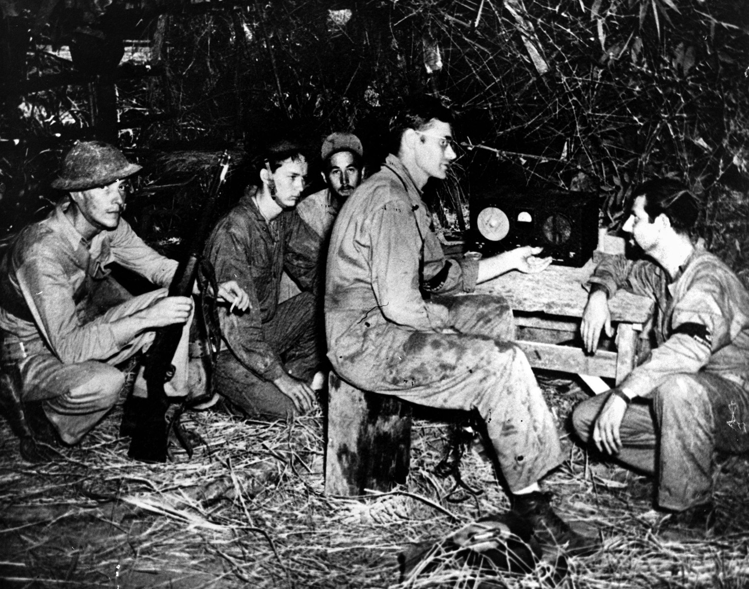 Anxious American soldiers, probably hoping for word on reinforcements, listen to the Voice of Freedom on the radio in the spring of 1942. Reinforcements never materialized.