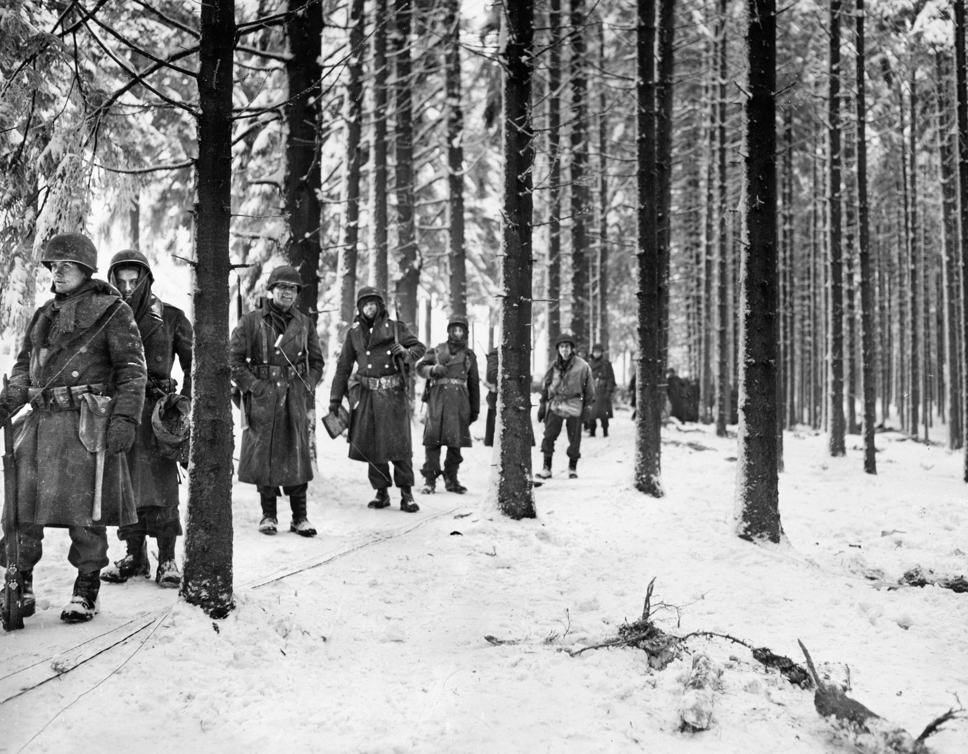 Soldiers of the 290th Infantry Regiment, 75th Infantry Division march through a Belgian woods during the Battle of the Bulge. It was in a forest like this that Staff Sergeant Darrell Bush tried to carry a fellow scout off the battlefield until he took a bullet from Germans firing down from the trees.