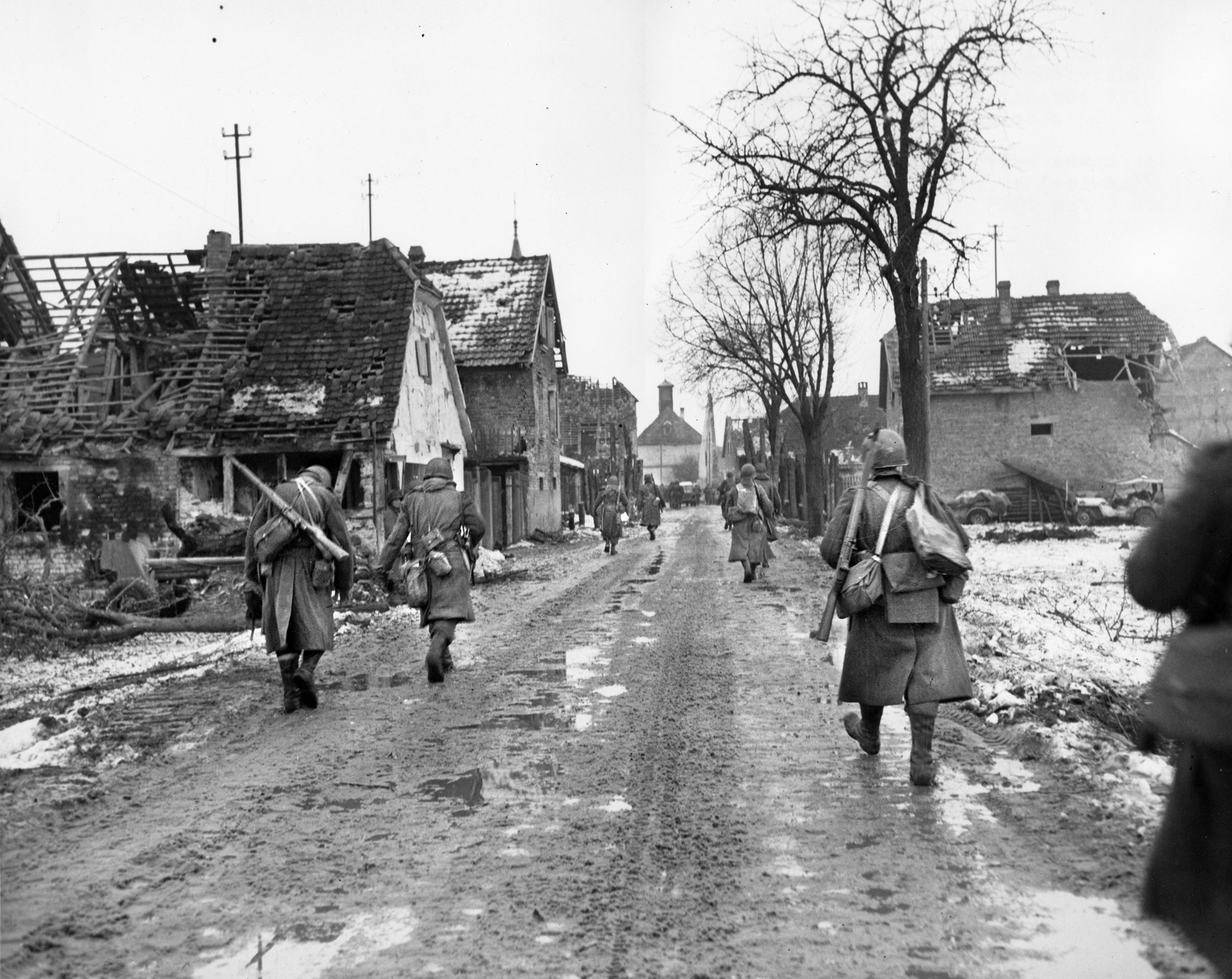 Soldiers with the 75th Infantry Division march through a Belgian town as they drive back the Germans. Bush, in an effort to get out of conditions like this, eventually found himself fighting in Bastogne with the 101st Airborne Division.