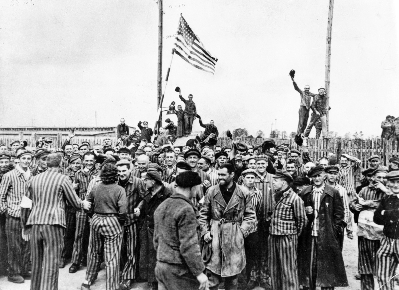 Prisoners of Dachau celebrate their freedom after American forces liberate the camp. Bush carried prisoners out of the camp on his back. The experience gave him claustrophobia.  