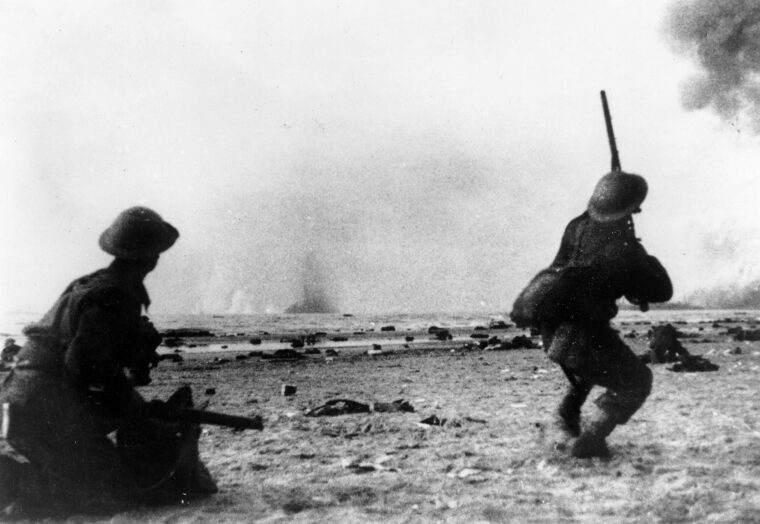 A British soldier awaiting evacuation on the beach at Dunkirk points looks for low-flying German aircraft harassing the trapped soldiers of the BEF.