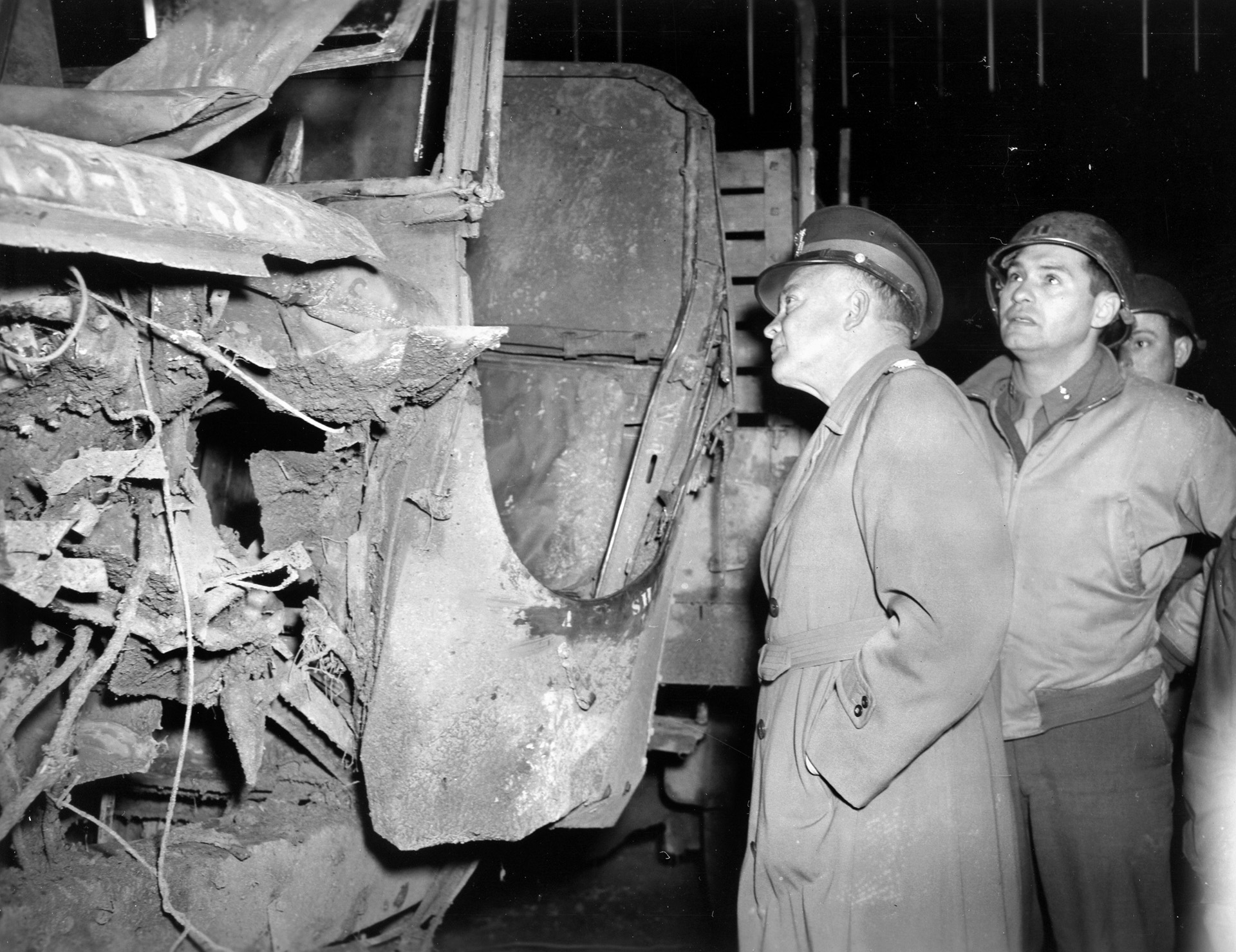 Eisenhower examines a damaged 2-and-a-1/2-ton truck that had run over a land mine.
