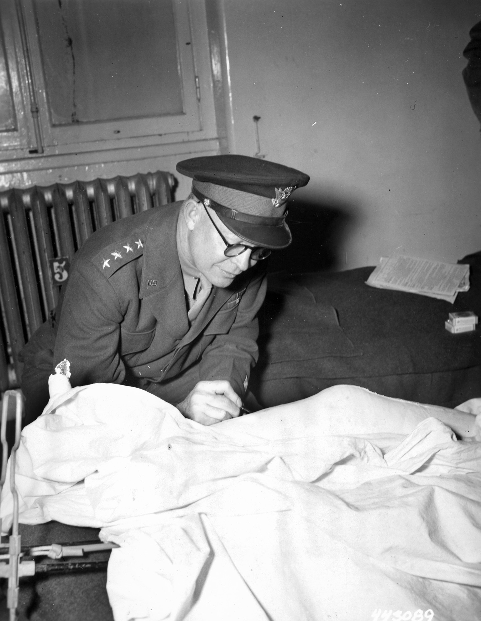 Never one to stand on protocol, Eisenhower autographs a cast on the leg of Pfc. John T. Dietz of Manchester, Connecticut, at the 12th Evacuation Hospital.