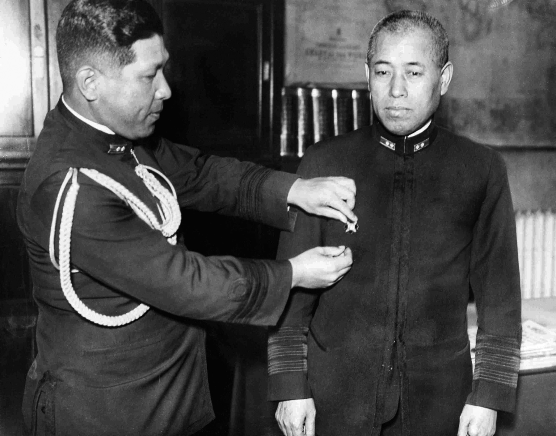 After suffering wounds at the Battle of Tsushima, Yamamoto received the wound badge. In this photograph, a Japanese naval officer adjusts the decoration on his tunic.