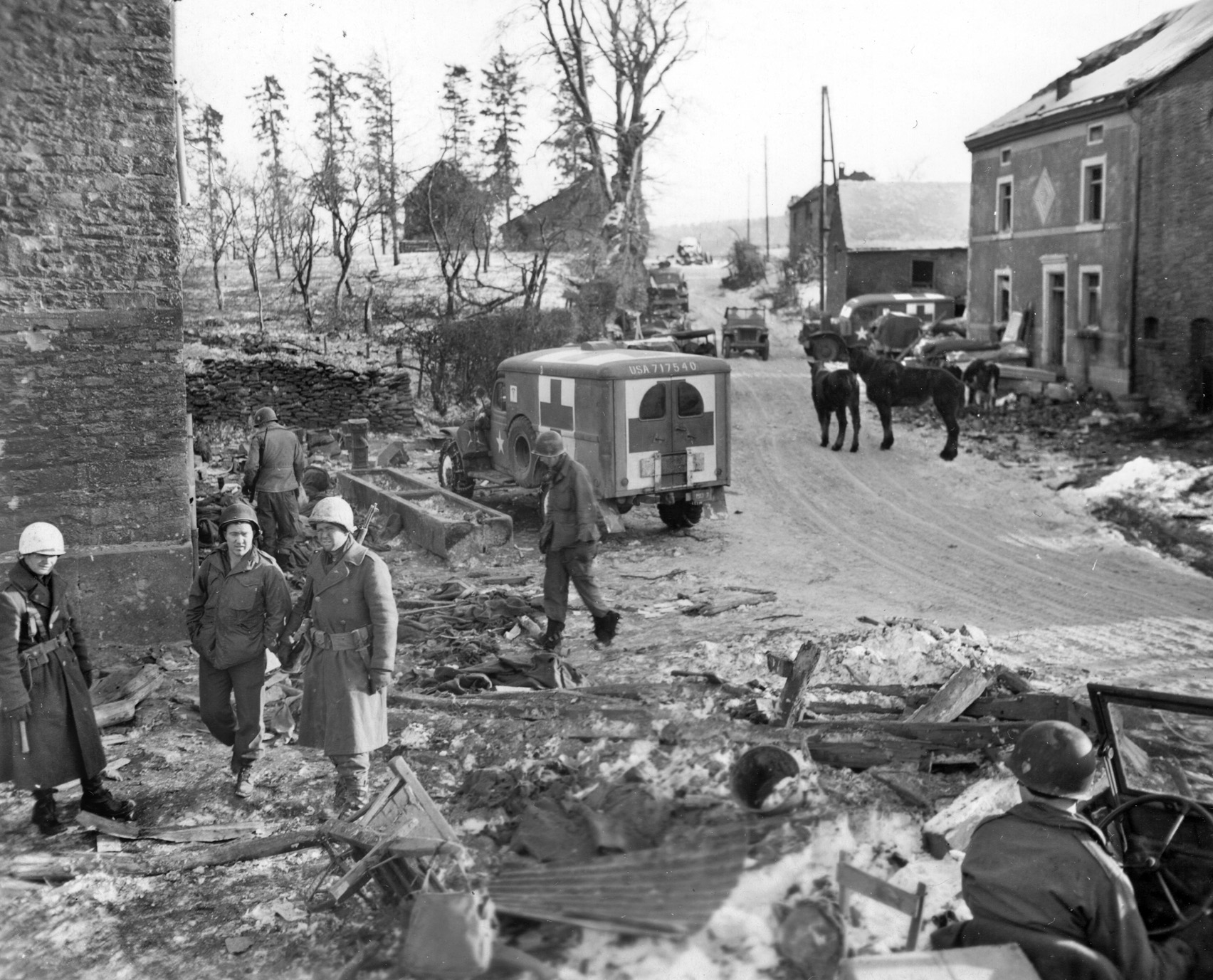 Paratroopers of the 101st inspect war-torn Foy, a mile north of Bastogne, after its capture by 506th Infantry Parachute Infantry, including Easy Company. Freeman was digging a mortar pit in the snow when he was summoned back to battle.