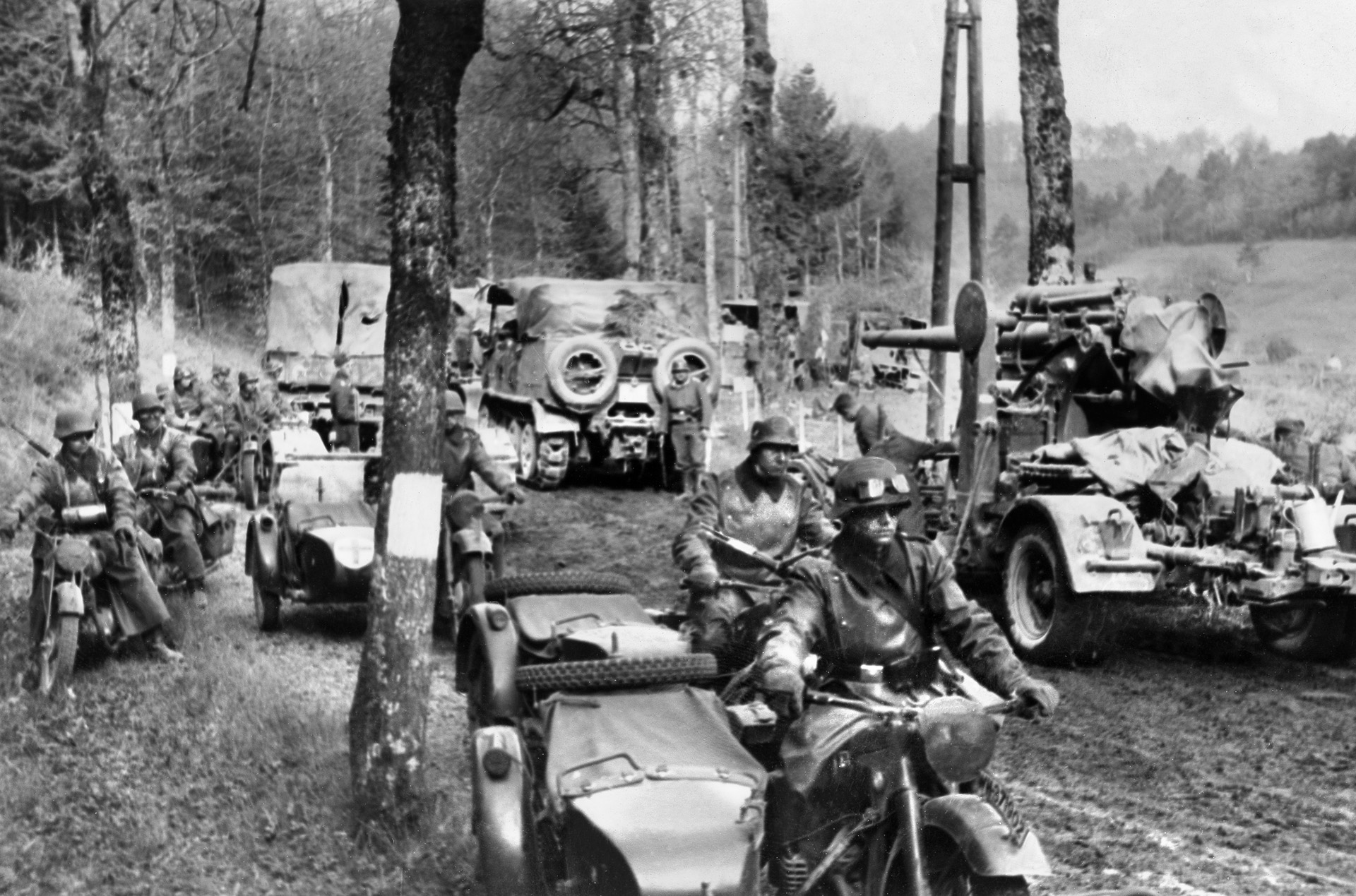 A German column, including armored and motorized vehicles, pauses momentarily as it penetrates the dense Ardennes Forest during the opening days of the attack. Allied planners before the war considered the Ardennes impenetrable.