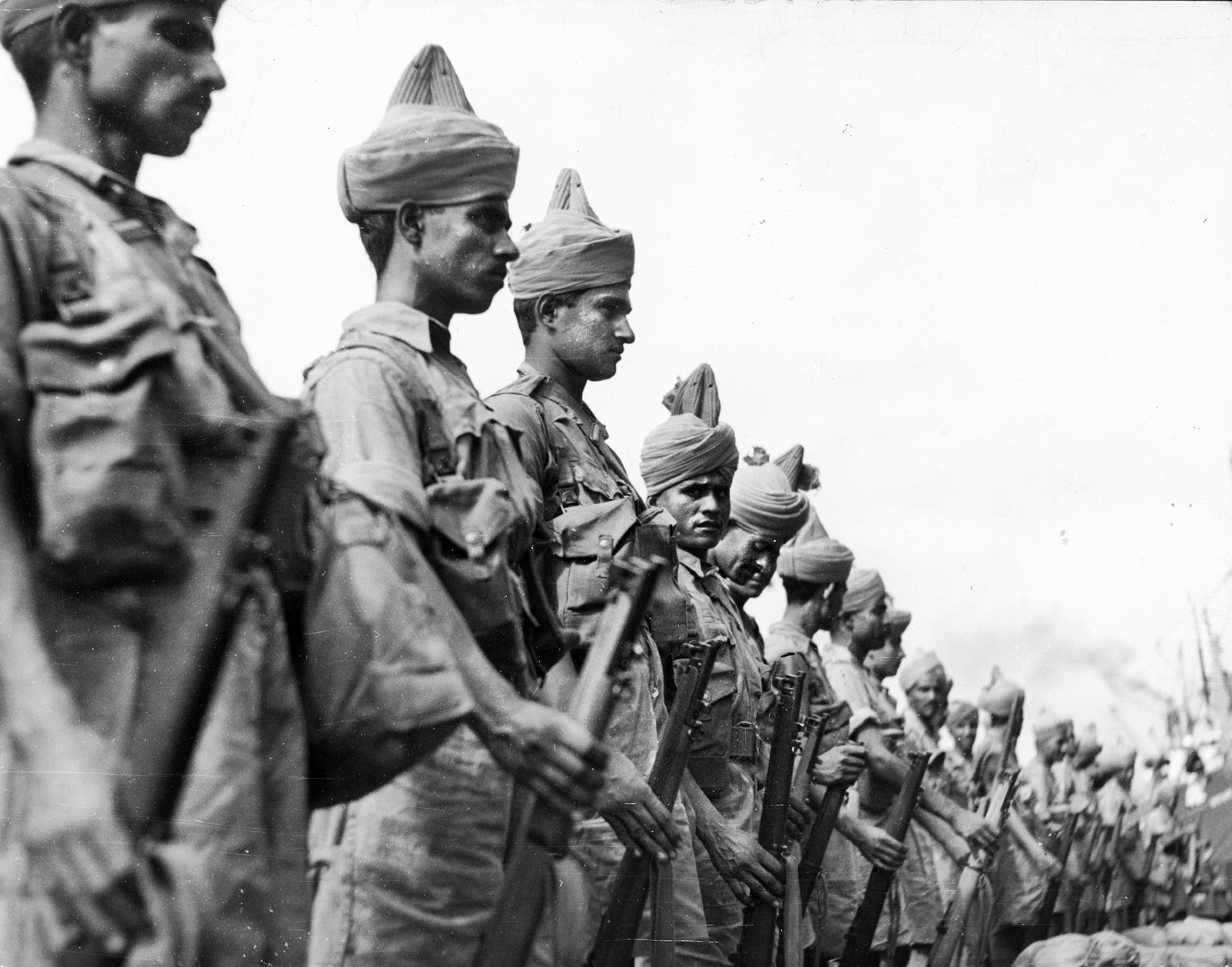 Soldiers of the Indian III Corps stand in ranks. The Indian formations were the primary ground force that opposed the Japanese during the lightning campaign to wrest the Malay Peninsula and the fortress of Singapore from their British and Commonwealth defenders.