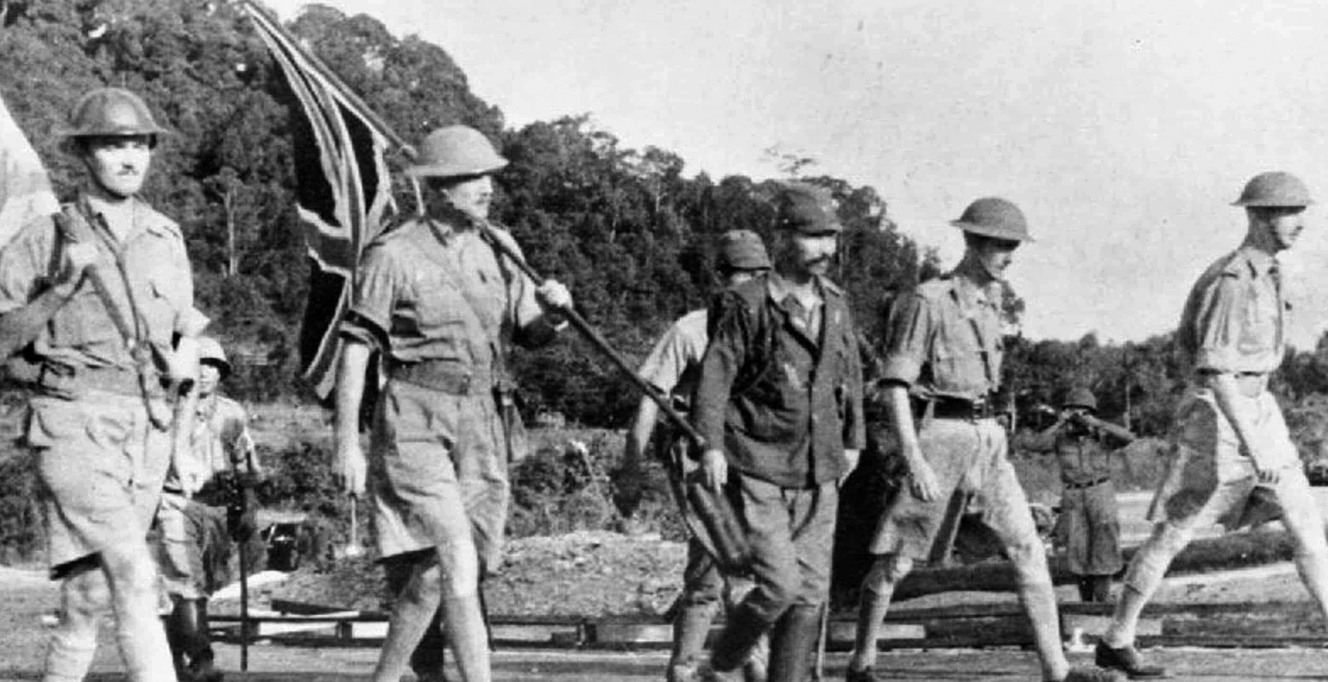 General Arthur Percival (far right) strides toward Japanese lines to discuss terms for the capitulation of the garrison of the great British colonial bastion of Singapore on February 15, 1942. Somber British soldiers carry the Union Jack and a flag of truce as they walk beside an escorting Japanese soldier.