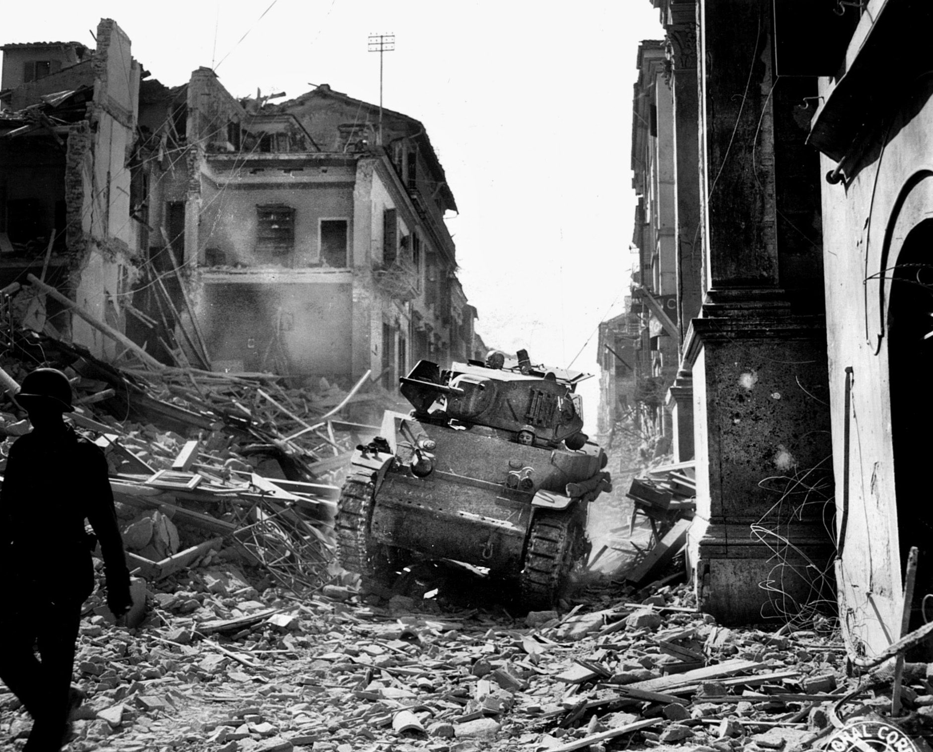A Stuart tank of the 1st Armored Division traverses a rubble-strewn street in Italy while probing for enemy positions. 