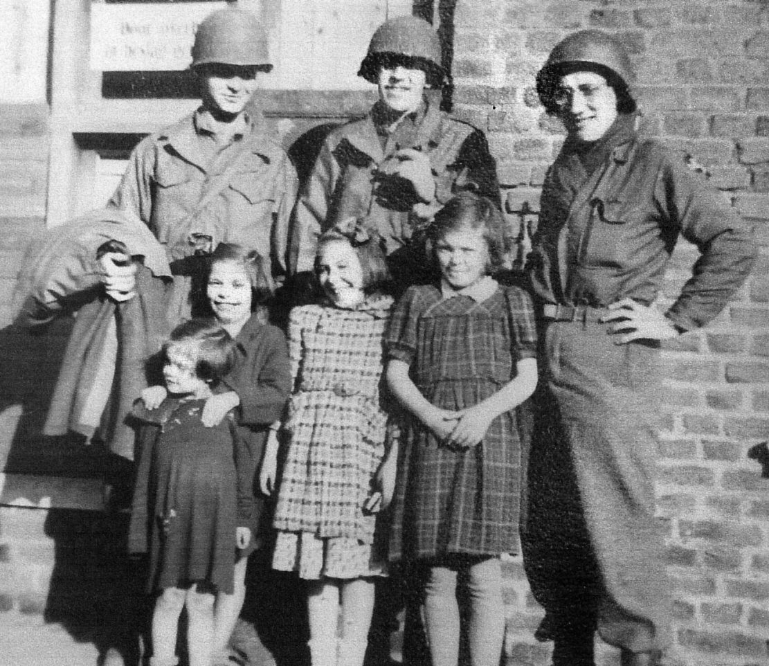 Henry Kissinger stands at right with other American soldiers as they befriend a group of German children during World War II.