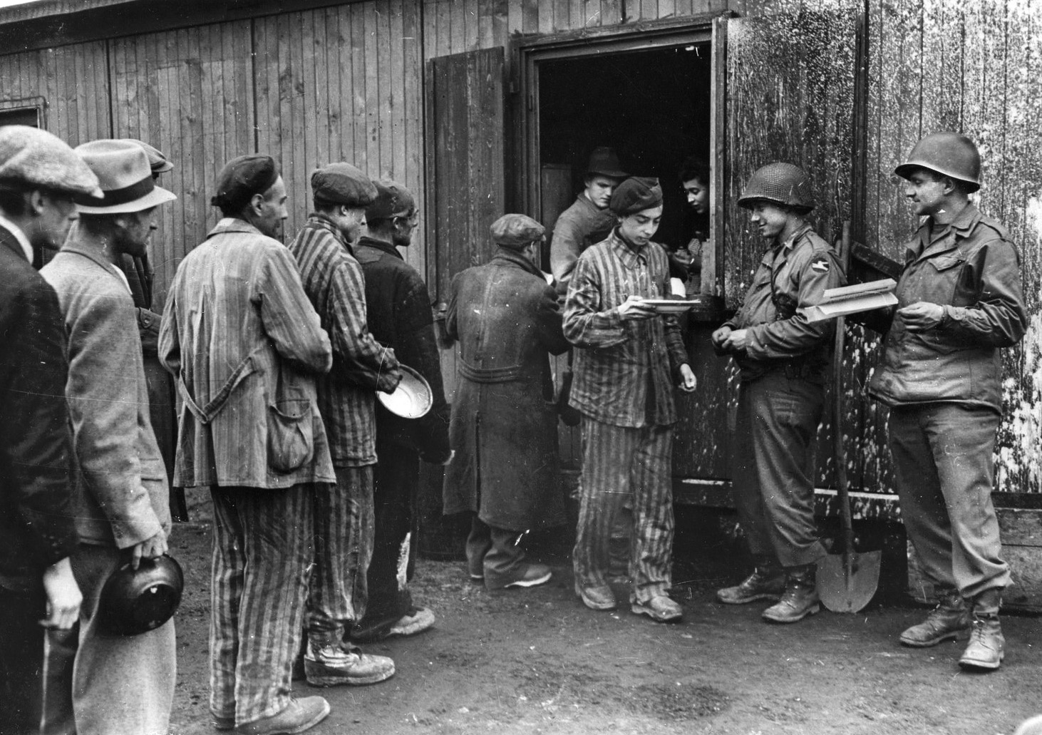Newly liberated Polish prisoners of the Nazi concentration camp at Hanover-Ahlem queue up to receive rations of soup from American soldiers.