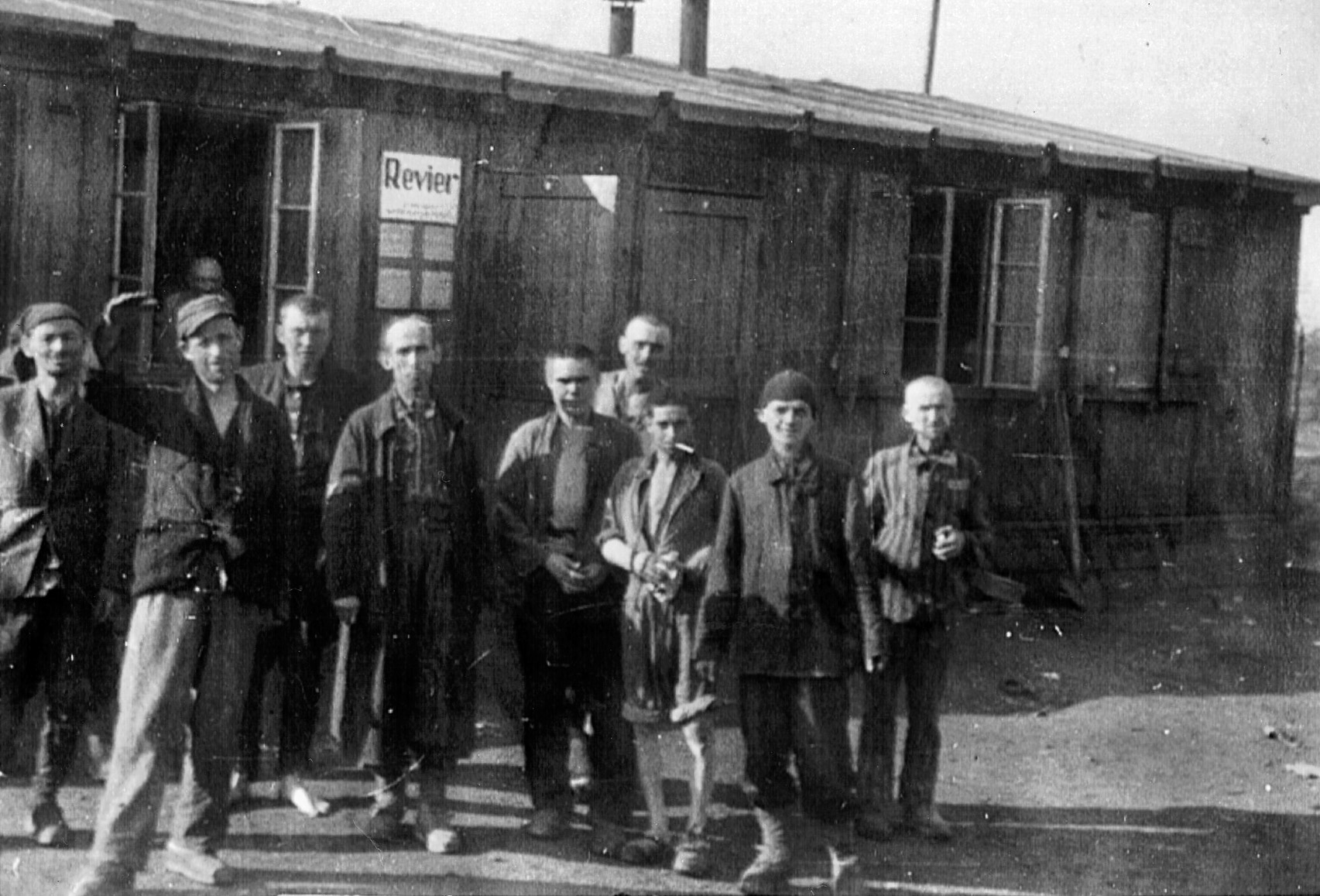 Their faces scarred with the horror of their experience, former prisoners of the Nazi concentration camp at Hanover-Ahlem pose outside the infirmary that has been established to provide medical care.