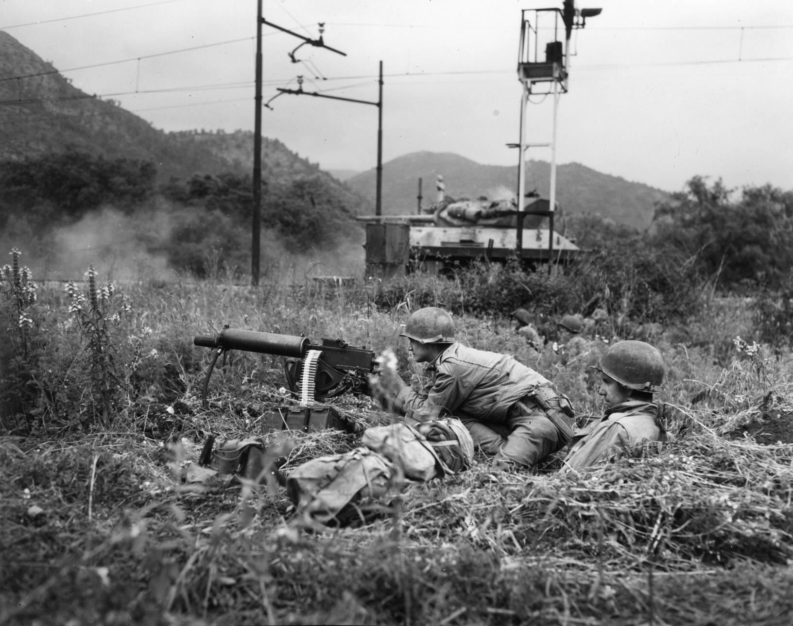 An American M10, open-turreted tank destroyer has opened fire on a German position at the Galleria di Mont Orso tunnel, where two enemy battalions have been trapped inside. An American soldier is ready to fire his .30-caliber machine gun if the Germans emerge to fight. 