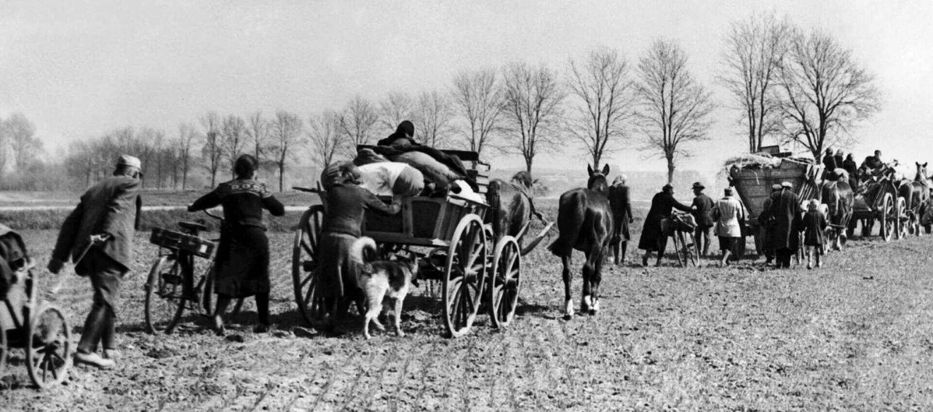 With their possessions piled into horse-drawn wagons, German civilians flee in an orderly line to a place of hoped-for safety.