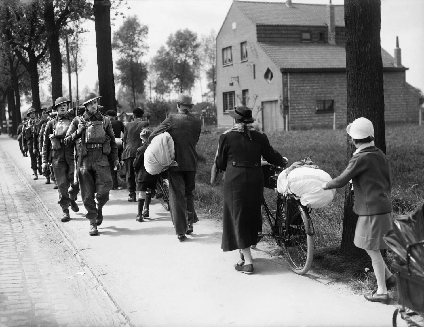 British troops march toward the front on May 12, 1940, two days after the German onslaught began as Belgian refugees stream away from the advancing Germans. Within days the British would also be in retreat before the swift enemy offensive.