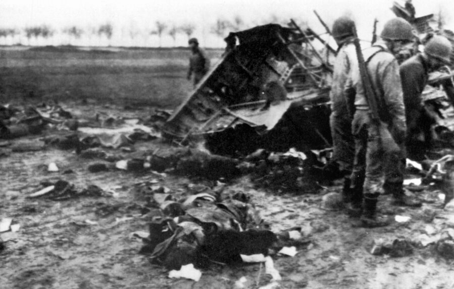 Investigating the wreckage of a Ju-52 shot down by antiaircraft fire, U.S. soldiers pause as they encounter the bodies of dead German paratroopers, December 17, 1944.