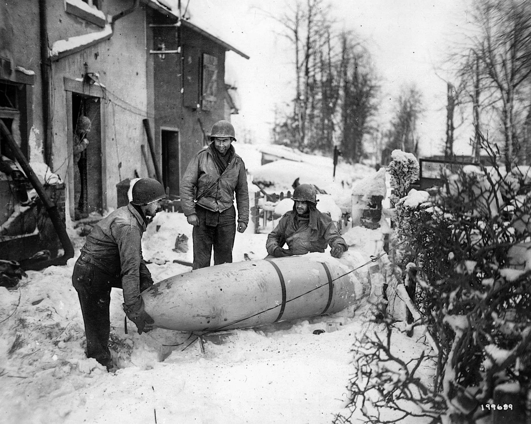 American soldiers of the 1st Division move a German supply container dropped near Bullingen, Belgium, January 1945.