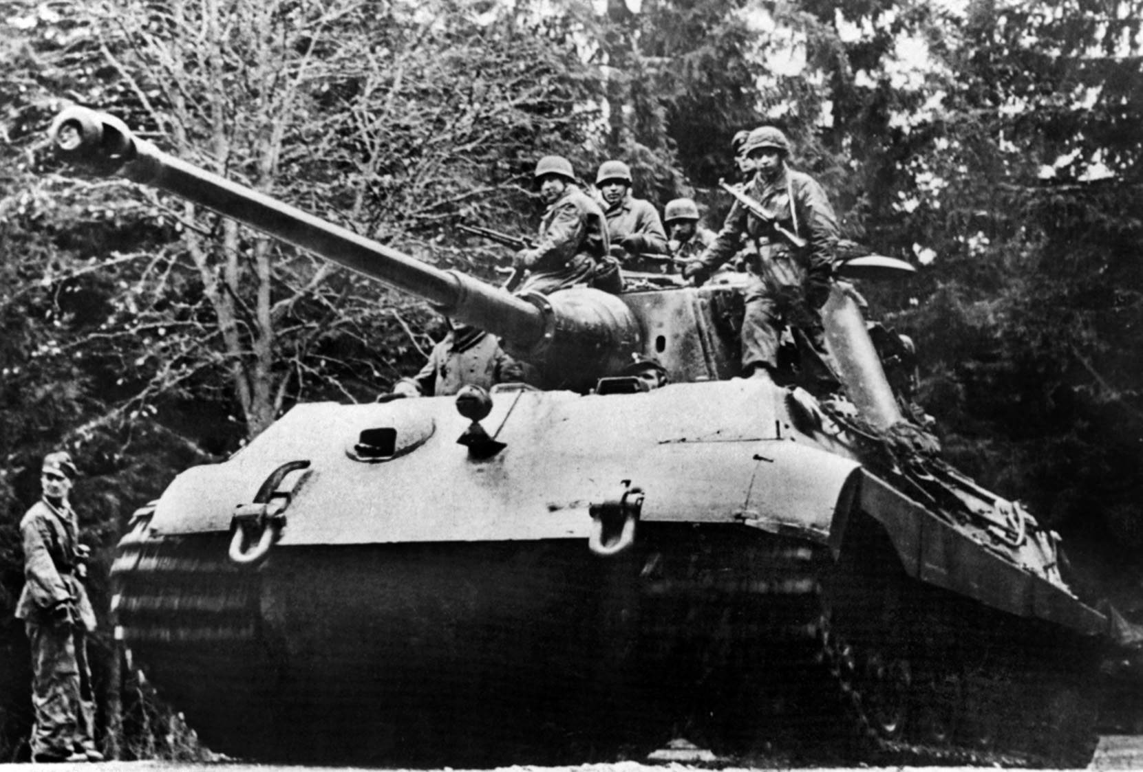German parachutists ride aboard a massive Tiger II tank, one of hundreds used during the Battle of the Bulge.