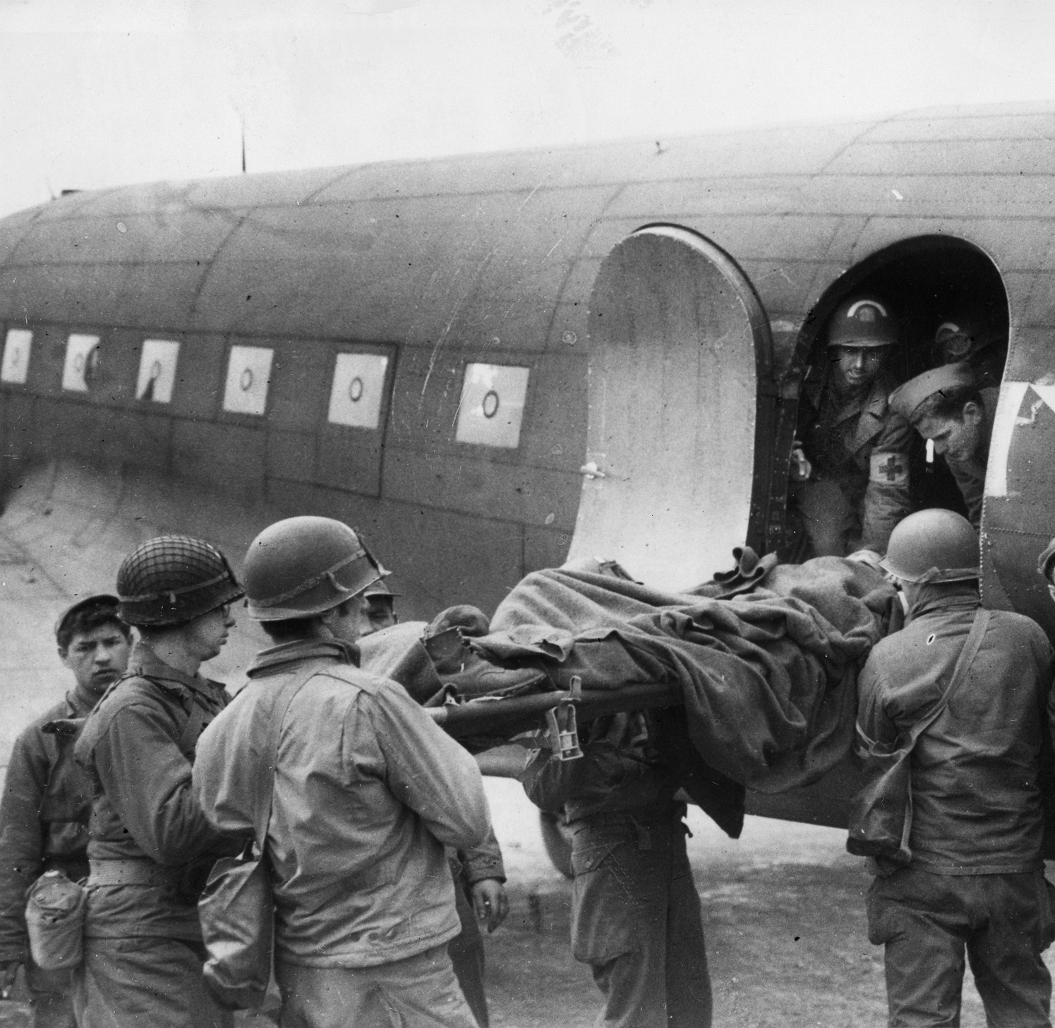 The C-47 served as a cargo plane and troop transport throughout the war, and large numbers of  the aircraft, the military conversion of the Douglas DC-3 civilian airliner, were constructed. In this photo,  a wounded soldier on a stretcher is being lifted aboard a C-47 for evacuation from France to England.