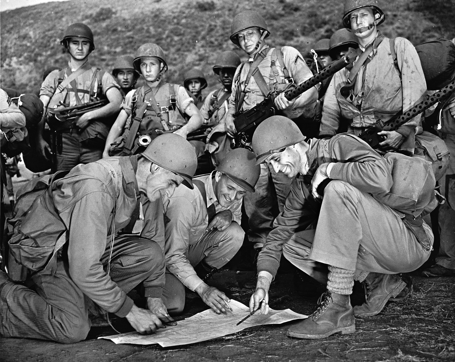 Colonel Evans F. Carlson (left) confers with Lieutenant Merwin Plumley (center) and Major James Roosevelt (right) during training in the days leading up to the raid on Makin Atoll. In this image the officers are consulting a map while the Marines at right are both holding Browning .30-caliber air-cooled machine guns.