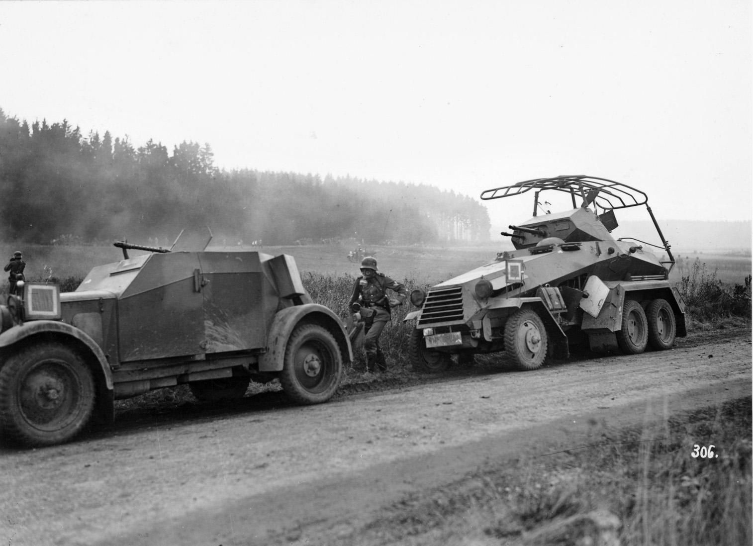 Reconnaissance troops participate in an exercise in 1936 with an SdKfz.13 open-topped armored scout car armed with an MG-13 machine gun and a SdKfz.232 six-wheeled heavy armored scout vehicle featuring a fully rotating turret with a 20mm autocannon and an MG-13 machine gun.