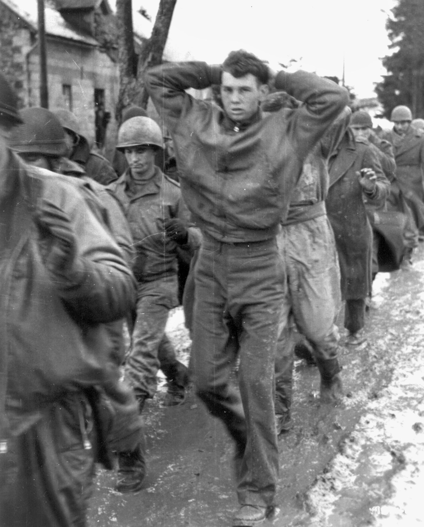 A young American prisoner of war with a look of fear and consternation on his face marches toward the rear with his hands on his head. Soon after his capture, Bob Max was put to work with other prisoners repairing railroad tracks.