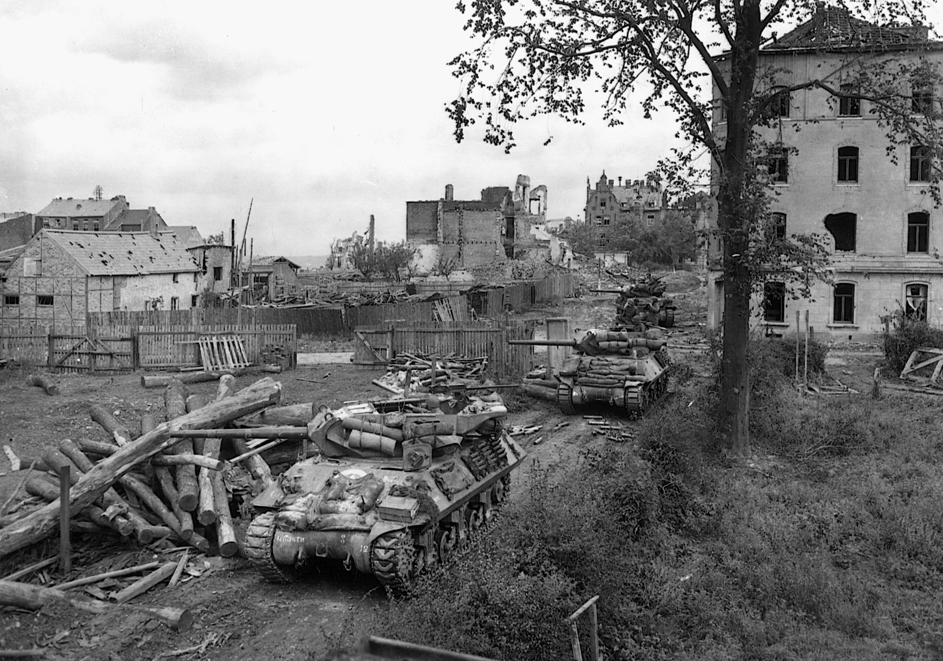 A line of M-10 tank destroyers prowls an Aachen neighborhood in search of blasting German observation posts. 