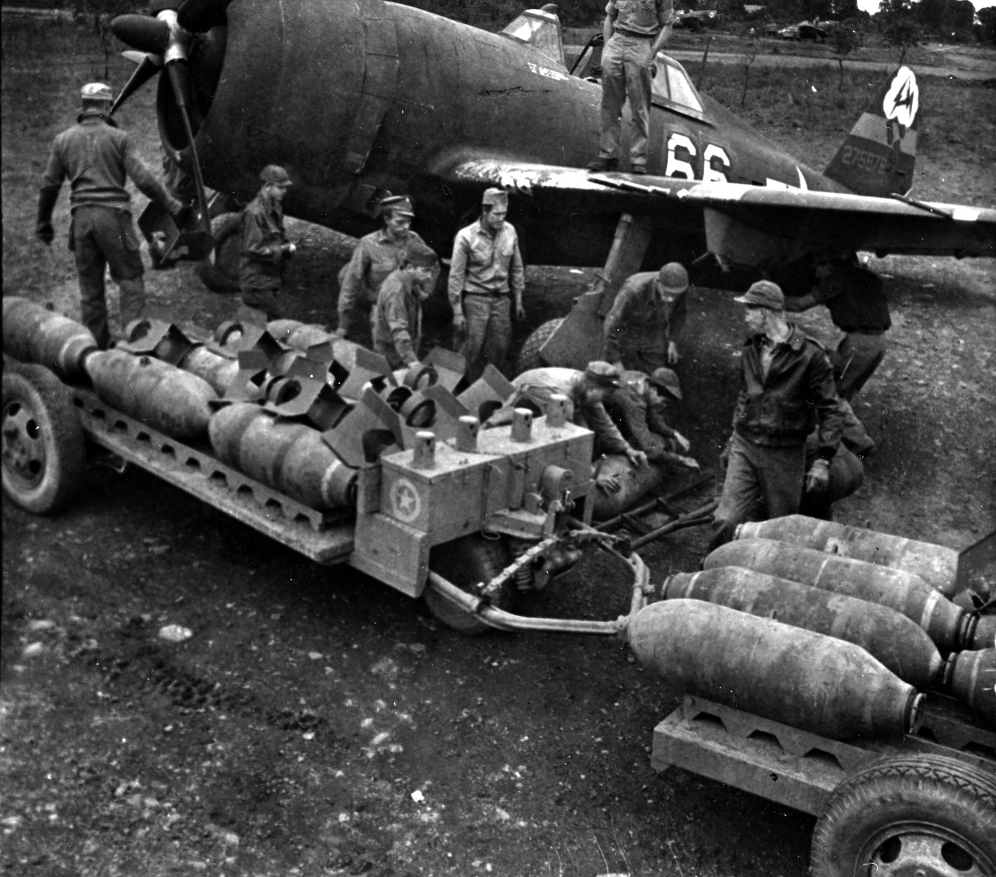 One of heaviest fighter aircraft of World War II, the Republic P-47 Thunderbolt, photographed at an airstrip in Italy, was a hefty radial-engine plane that could take severe punishment and bring its pilot safely home. The Thunderbolt was versatile, serving as an escort, dogfighter, and fighter bomber during the war. In this image ground crewmen prepare to attach bombs to hardpoints under a P-47D’s wings.