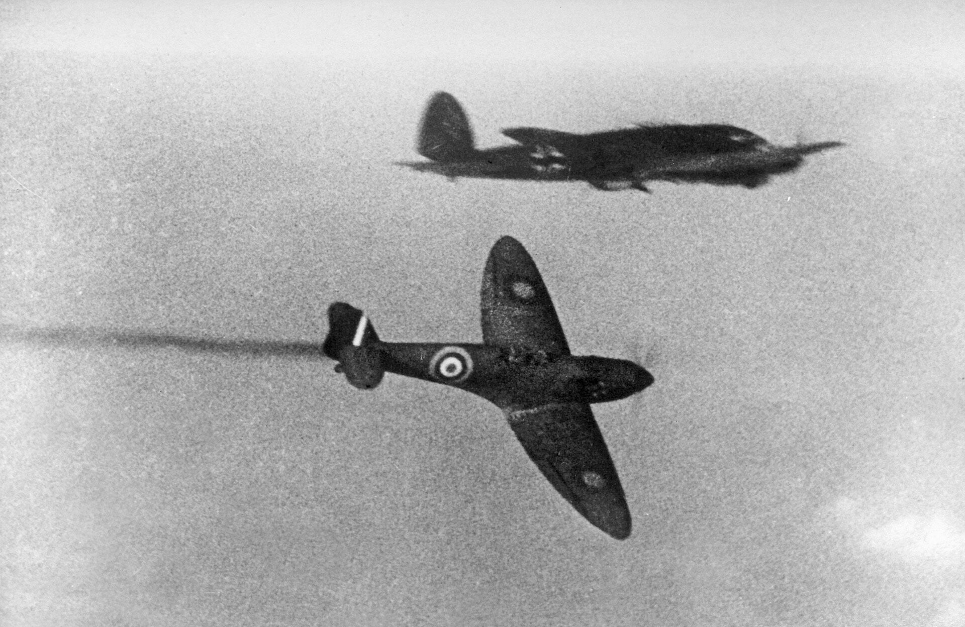 A Spitfire, trailing smoke, peels away after having engaged a Heinkel He-111 over the Channel.