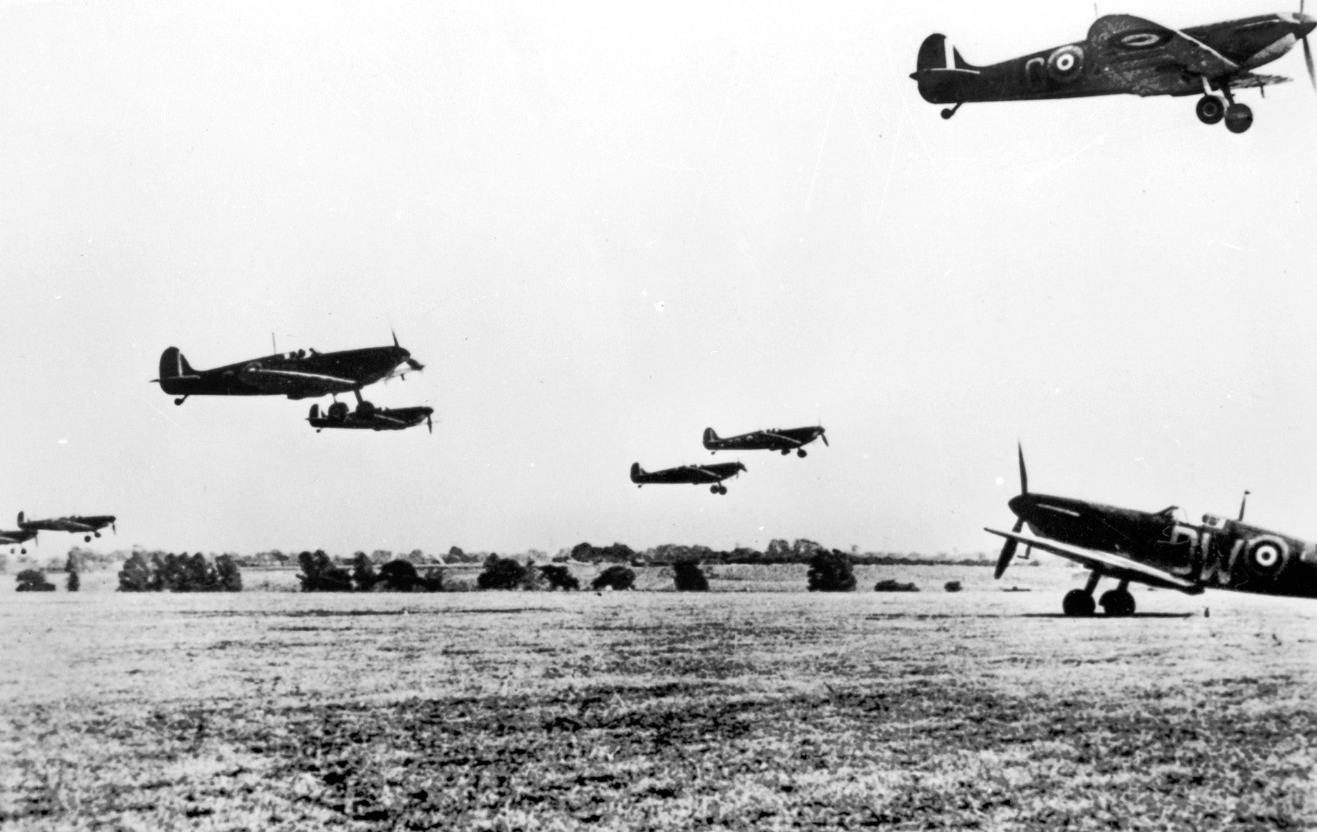 A squadron of Supermarine Spitfires scrambles into the sky after receiving an alert of approaching enemy aircraft. Many RAF fields were unpaved fields of grass, like this one.