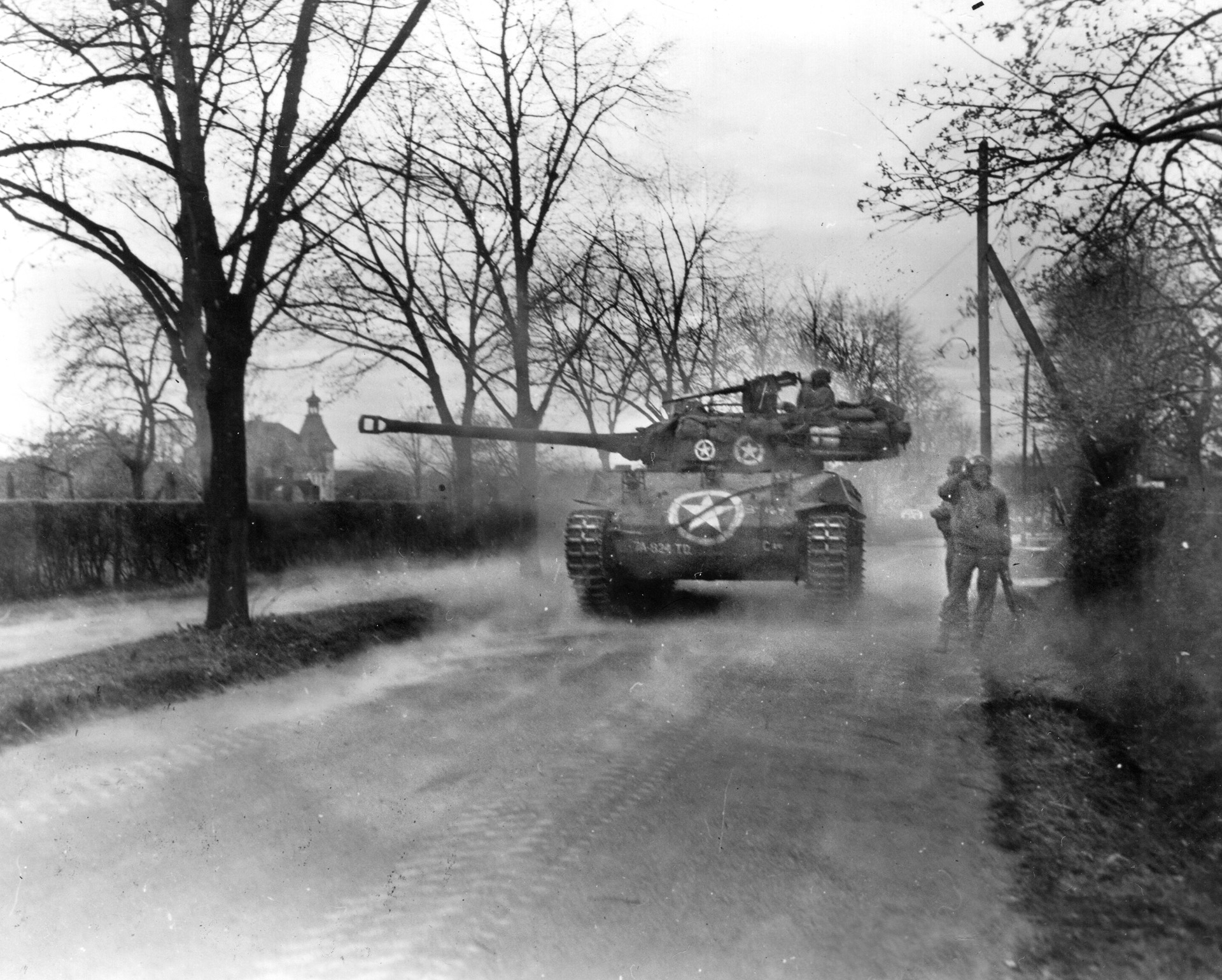 As men of the 397th Regiment look on, an M-18 tank destroyer fires in support of the assault on Wiesloch, Germany, April 1, 1945.