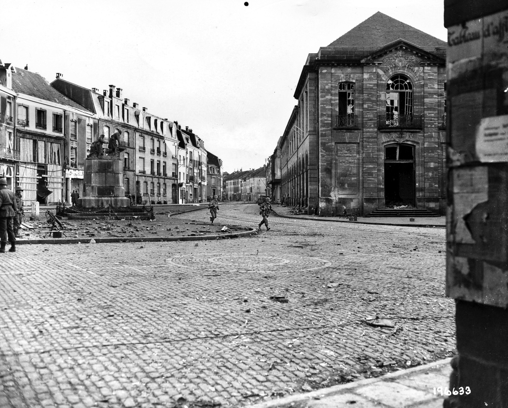 397th Regiment soldiers dash across a deserted intersection in Raon L’Étape; German resistance had not yet been overcome.