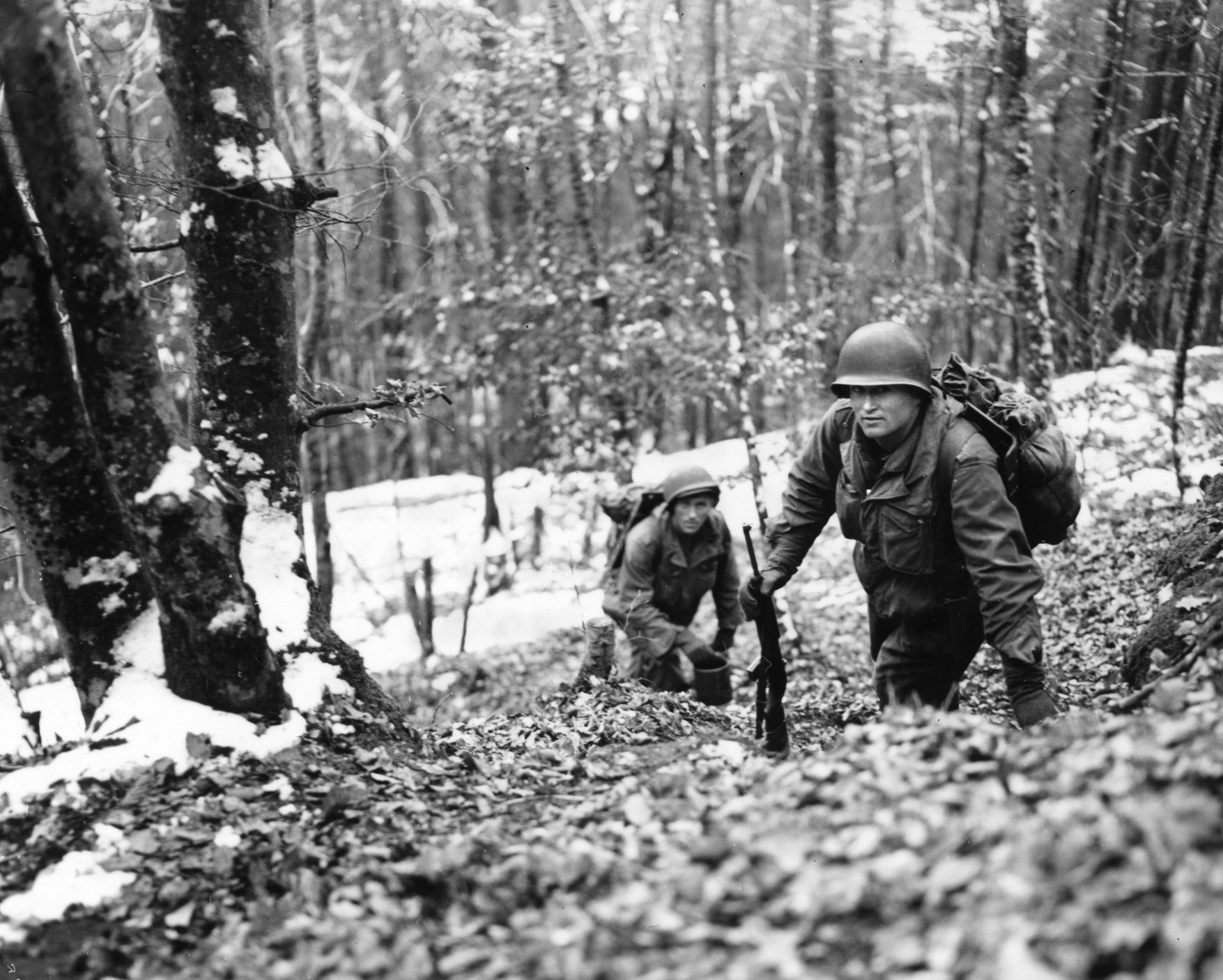 Working their way up a steep, snowy hill in the Vosges Mountains region of Alsace-Lorraine, men of the 45th Infantry Division prepare to attack the enemy. The 100th Division relieved the 45th in this area. Fighting in heavily wooded areas like this proved problematic.