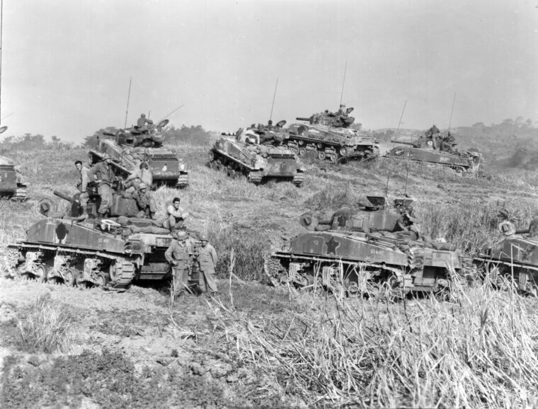 A group of American tankers of the 193rd Tank Battalion take a break on and around their M4 Shermans before returning to combat on Okinawa, April 1945. Note that the white stars on the sides of the tanks have been painted out to reduce their visibility to the enemy. Nevertheless, exceptionally strong Japanese resistance took a heavy toll on American tanks and tankers.