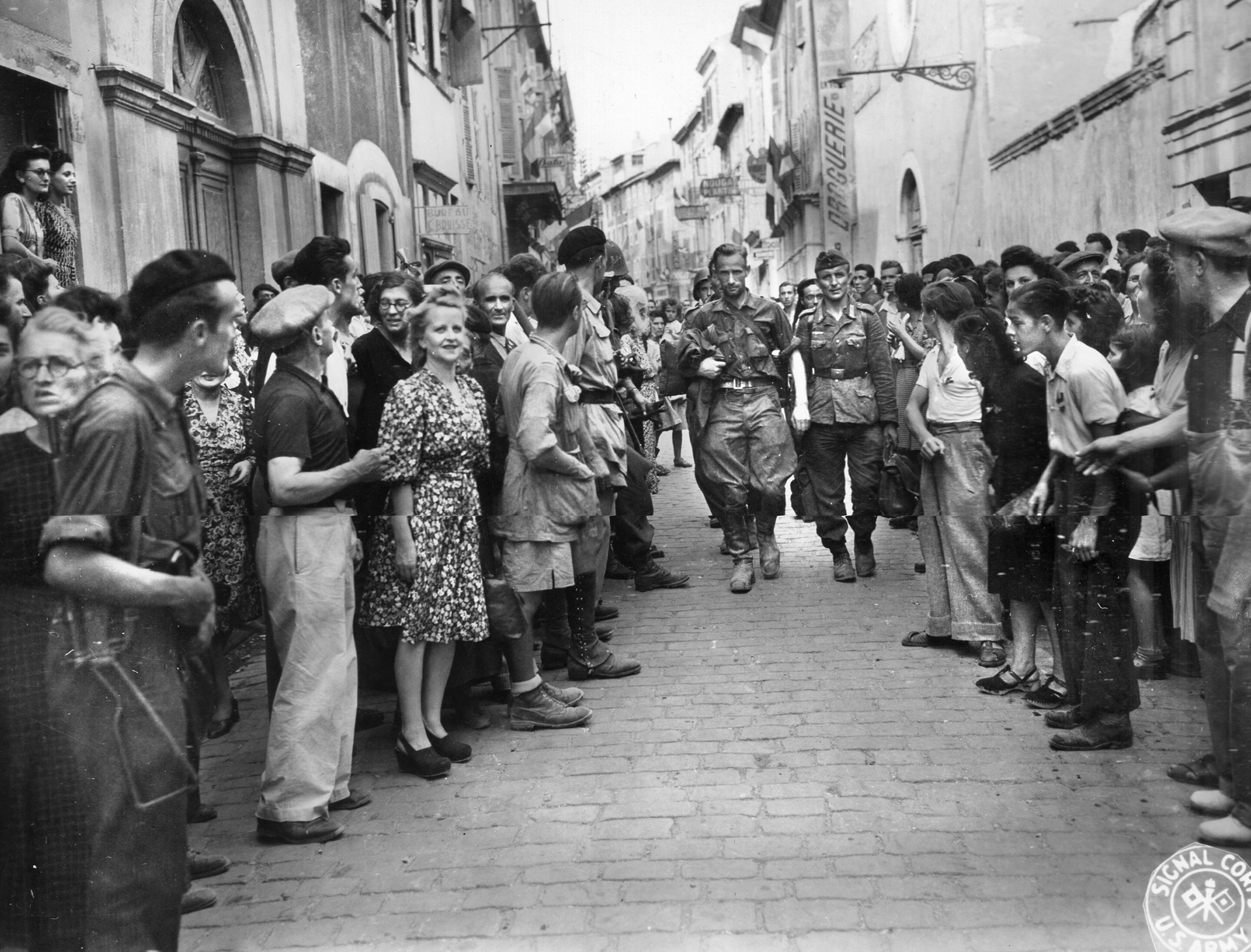 German snipers, disarmed and taken alive, are marched down a street in Montelimar while a crowd of townspeople looks on. 
