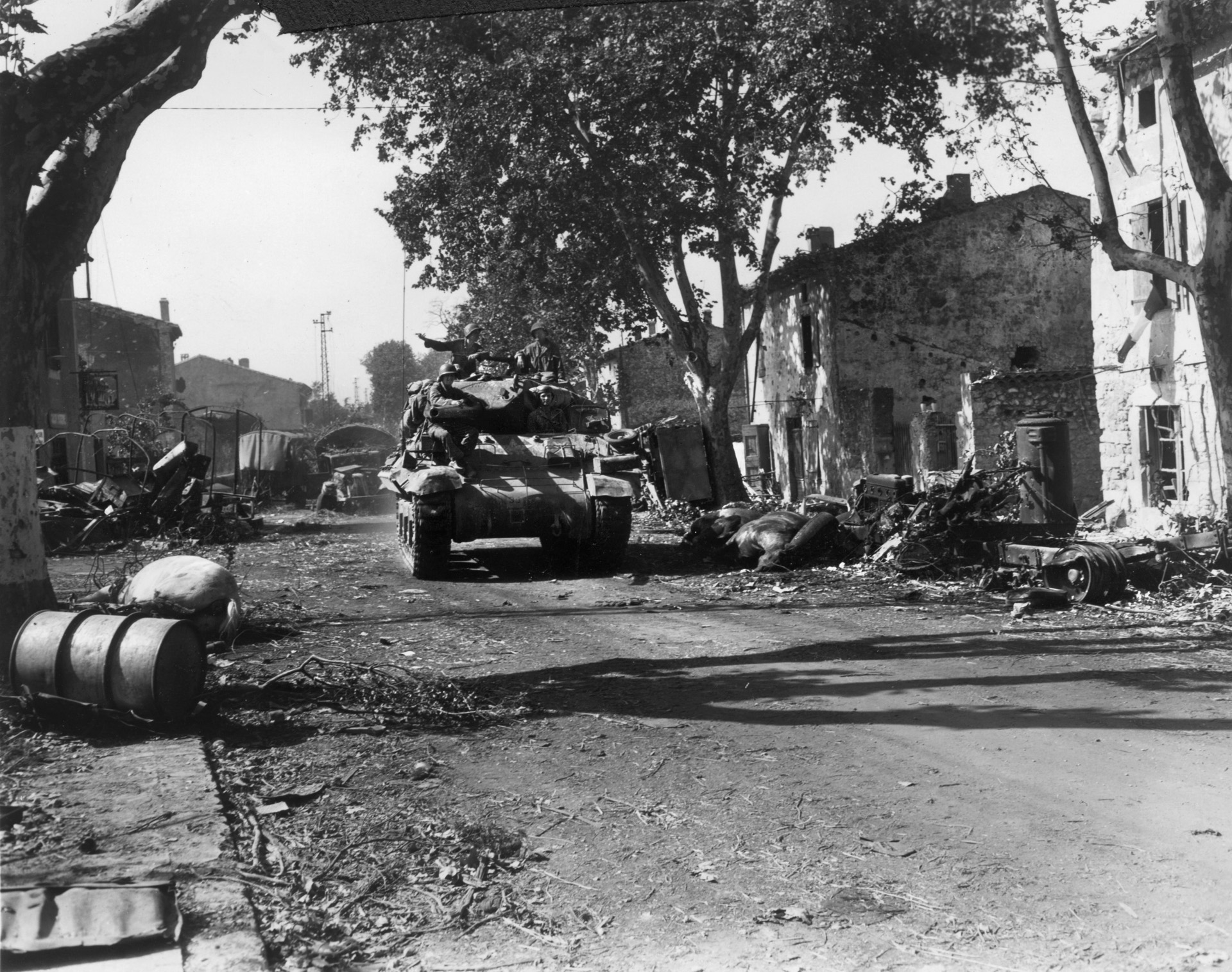 The wreckage of a German convoy, decimated by Allied air power north of Montelimar during Operation Anvil-Dragoon, litters both sides of the road as an American tank lumbers past. German forces in southern France continued their retreat after mounting a spirited defense in some areas.