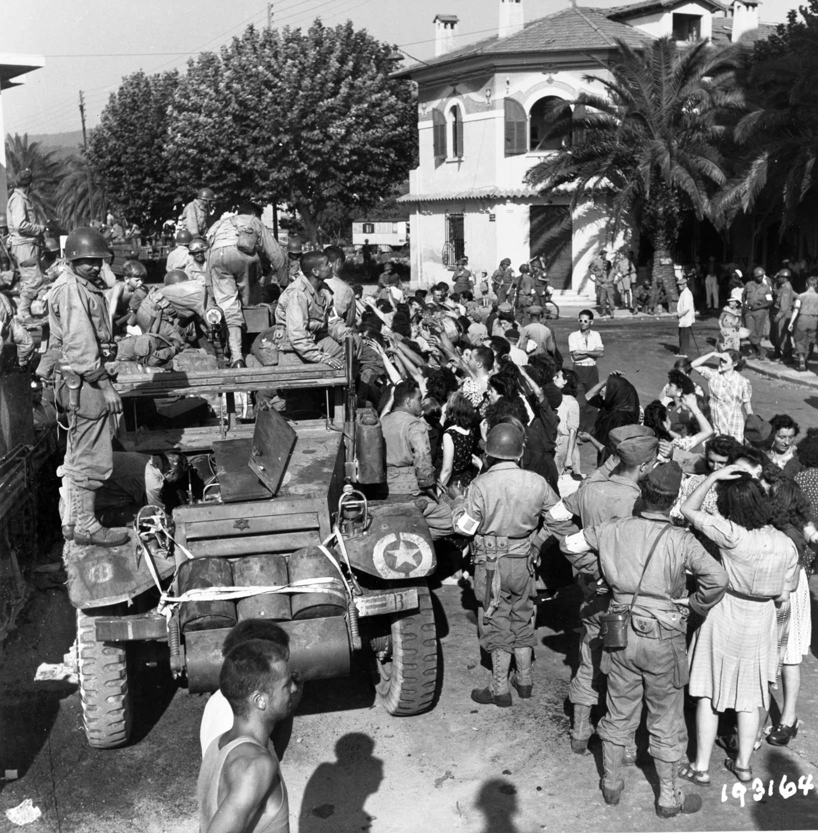 A crowd of civilians in the town of St. Maxime, France, welcomes a French tank-destroyer unit on August 16, 1944. They are wearing American uniforms and equipped with American arms, including this halftrack mounting a .30-caliber machine gun.