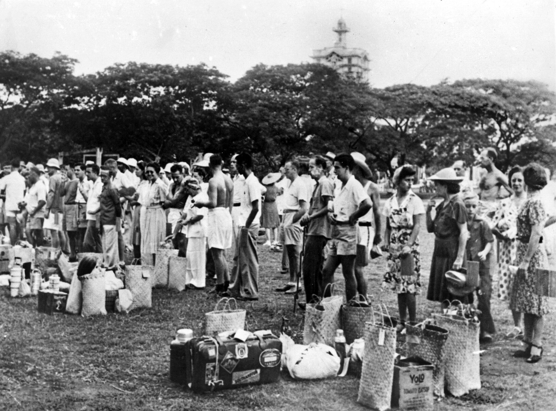 Following the fall of the Philippines in 1942, Americans and foreign nationals were rounded up by the victorious Japanese, and many were interned at Santo Tomas University.  In this photo, a group of internees gathers at the command of the Japanese, bringing along what few belongings they could carry.
