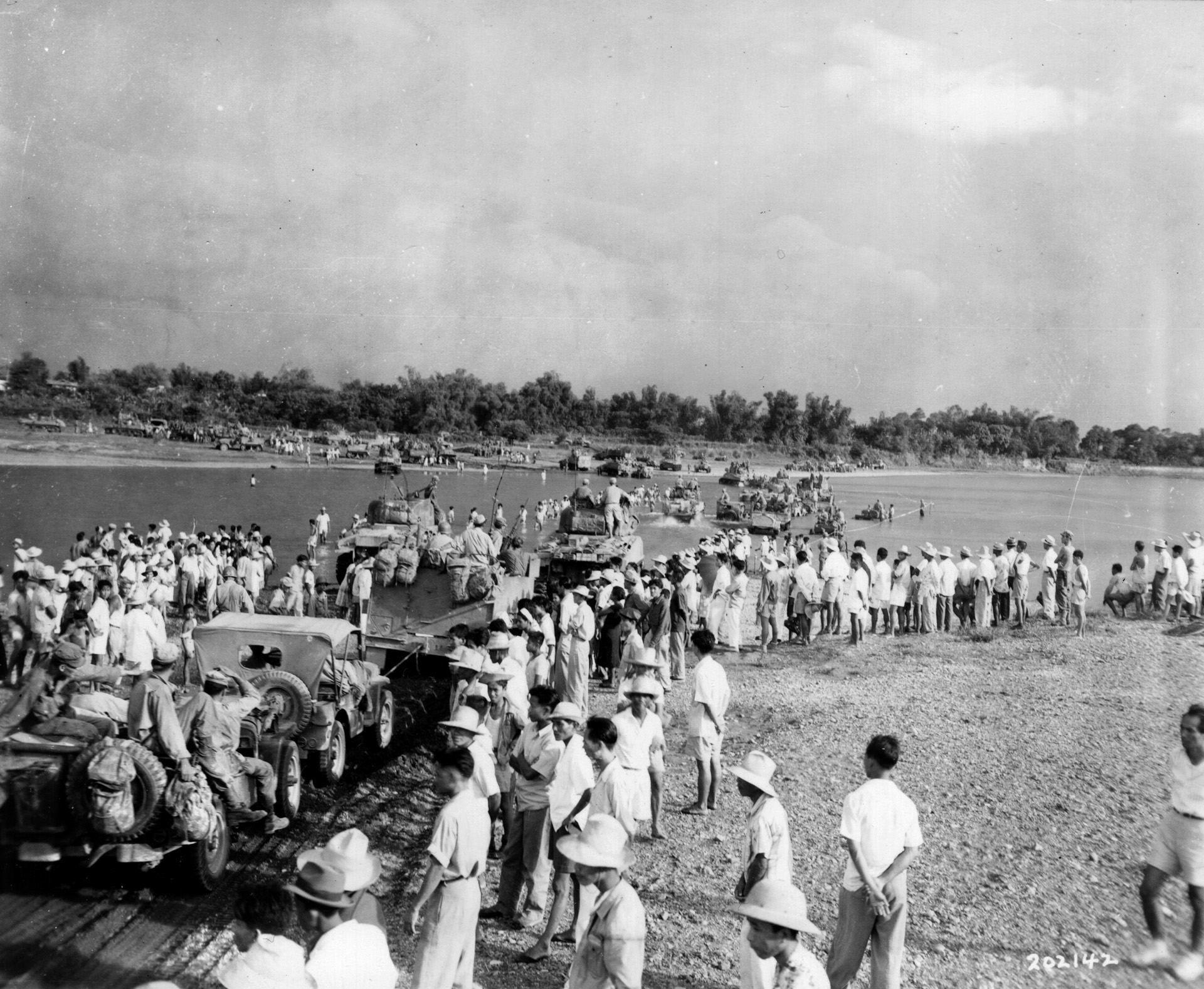 Twenty-five miles from Manila, American soldiers of the 1st Cavalry and Filipino civilians gather along the banks of the Angat River.