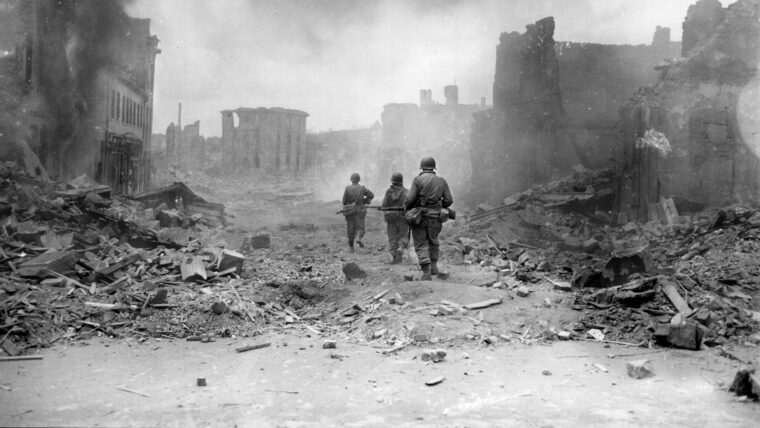 On March 20, 1944, soldiers of the 30th Infantry Regiment, 3rd Division proceed cautiously through the rubble of Zweibrucken, Germany. Some fires still burn in the devastated city.
