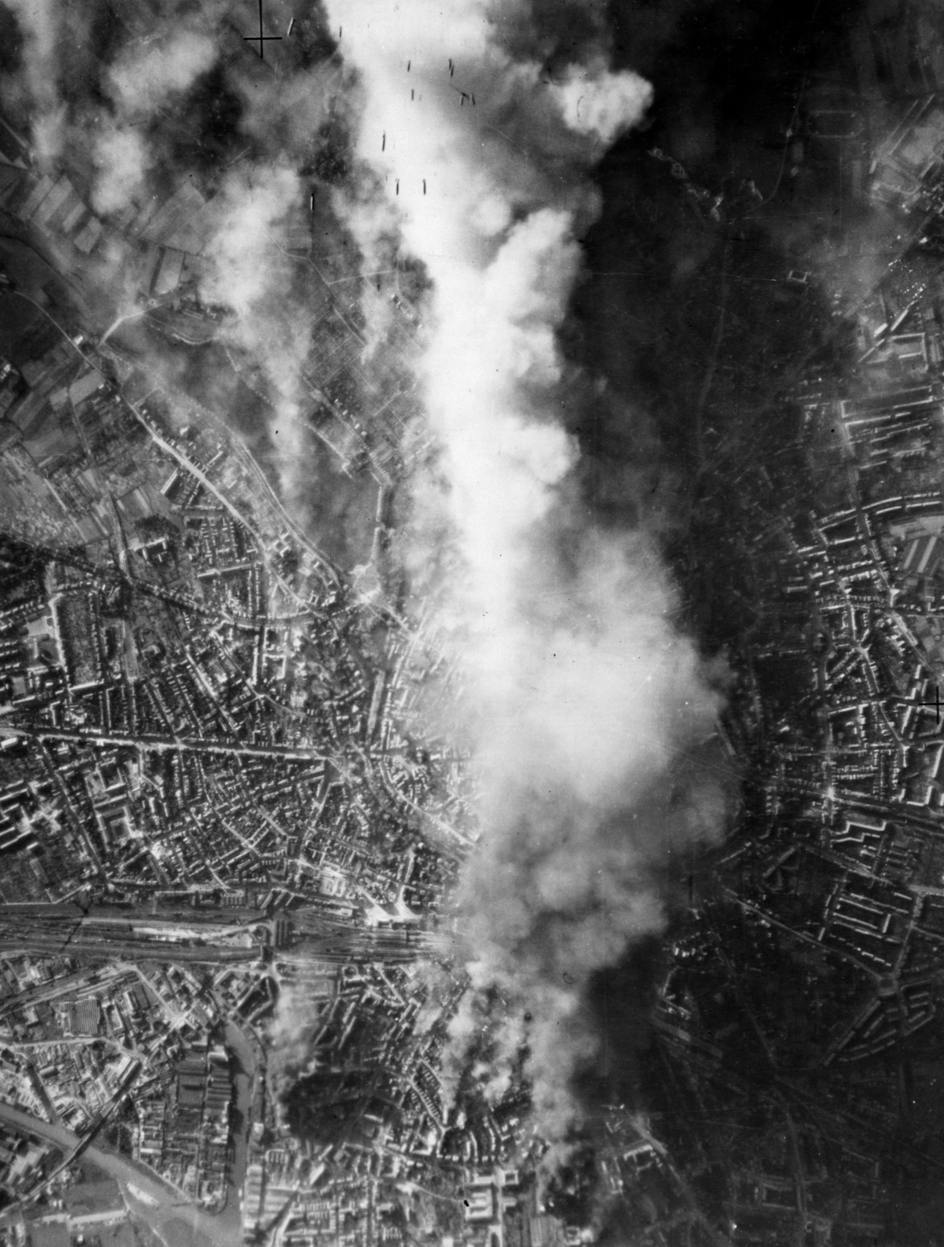 A pall of smoke and debris rises skyward while American bombs fall on a rail yard in Münster, Germany, on October 10, 1943. Civilians in Münster had been assured by German Home Air Defense that American bombers would not attack on a clear, cloudless day.