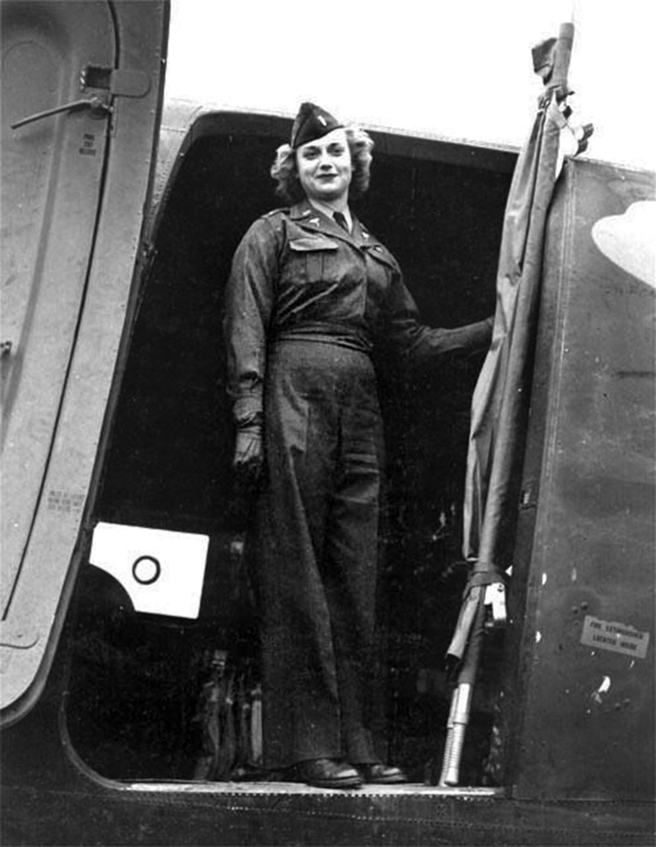 Nurse Reba Whittle stands at the door of a C-47 transport plane prior to departure. 
