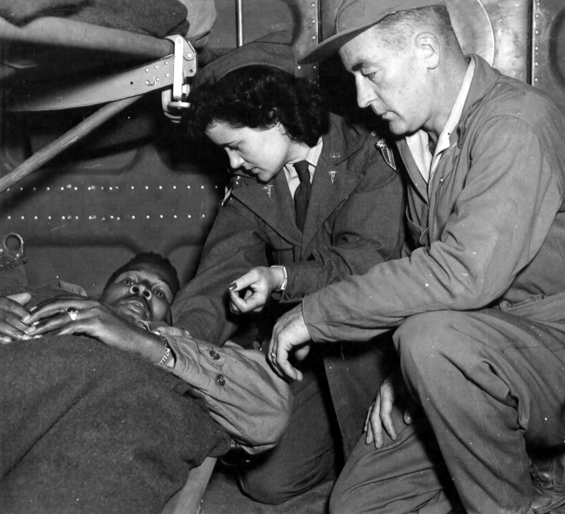 Lieutenant Pauline Curry, and medical technician, Sergeant Lewis Marker, see to the comfort of a patient during an evacuation flight in the skies over India.  Approximately 500 nurses served in 31 medical air evacuation squadrons during World War II. 