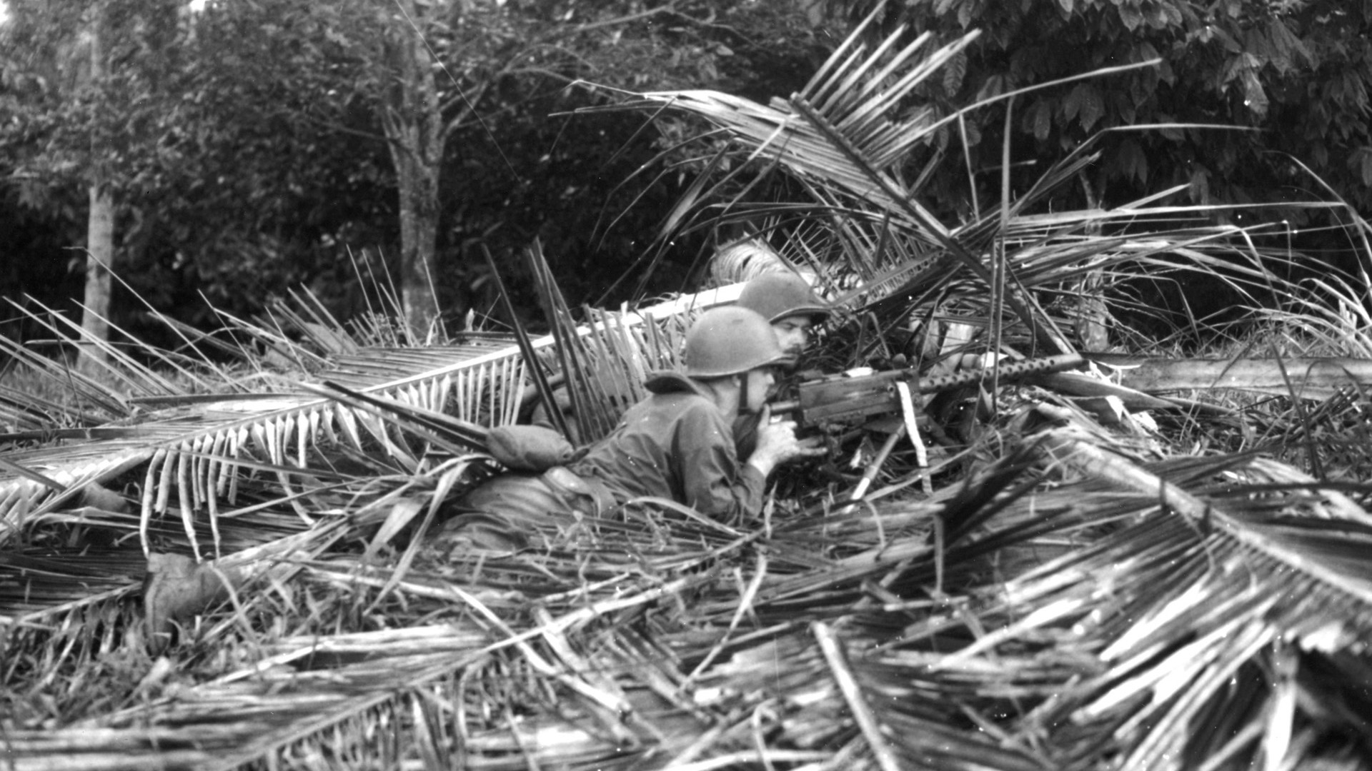 A Marine Raider machine-gun crew uses palm fronds to camouflage its position during intense training prior to the Makin Raid. The Marines fought heroically against a stout Japanese garrison on the atoll and withdrew after controversially considering surrender to the enemy.