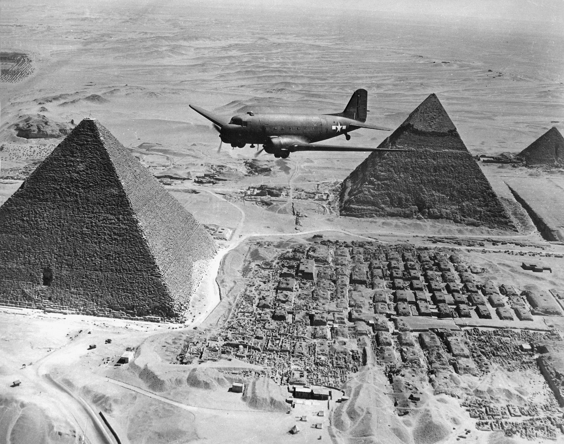 A Douglas C-47 Skytrain transport plane emblazoned with U.S. markings flies over the Pyramids at Giza, Egypt, in 1943.