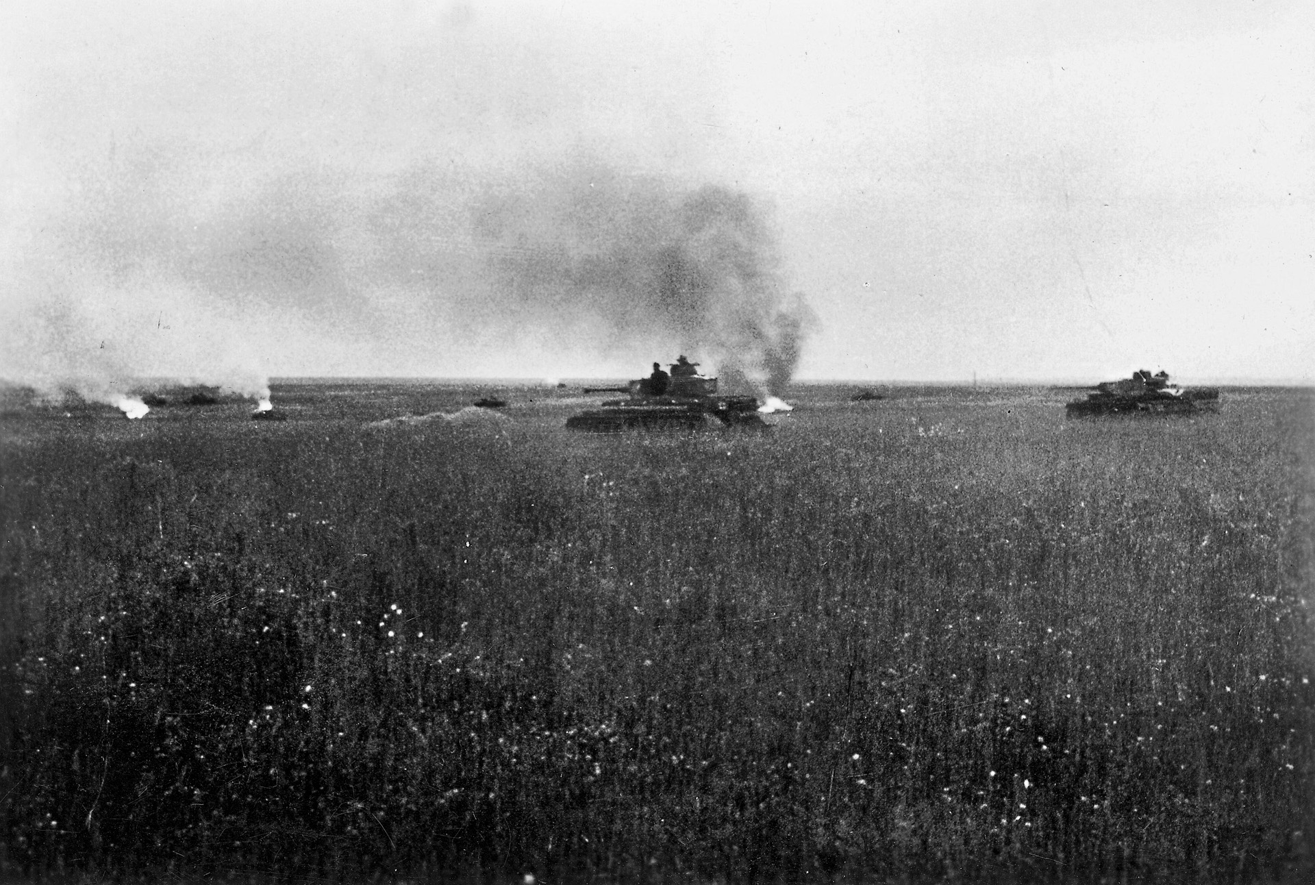 Plumes of smoke rise from disabled tanks and armored vehicles as German tanks move cautiously forward on the Russian steppe during the Battle of Kursk. 